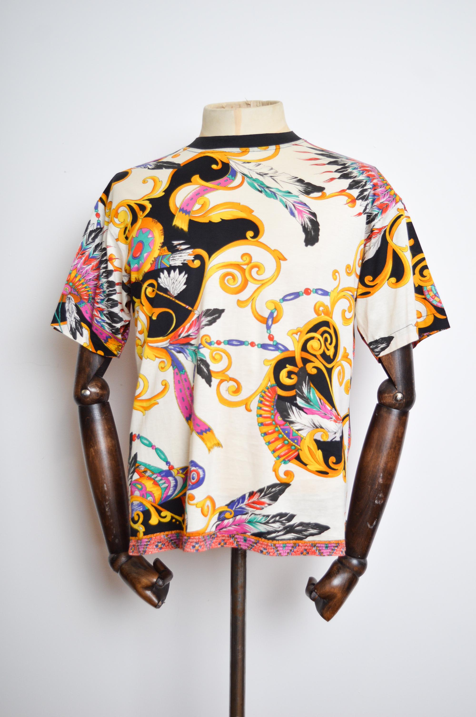 1990's Vintage 'VERSACE' short sleeved 'Native American' pattern T Shirt, crafted from a printed cotton with contrasting front and back panels. 

MADE IN ITALY.   

Features: rounded neckline, short sleeves, Versace tab detail in bottom corner,