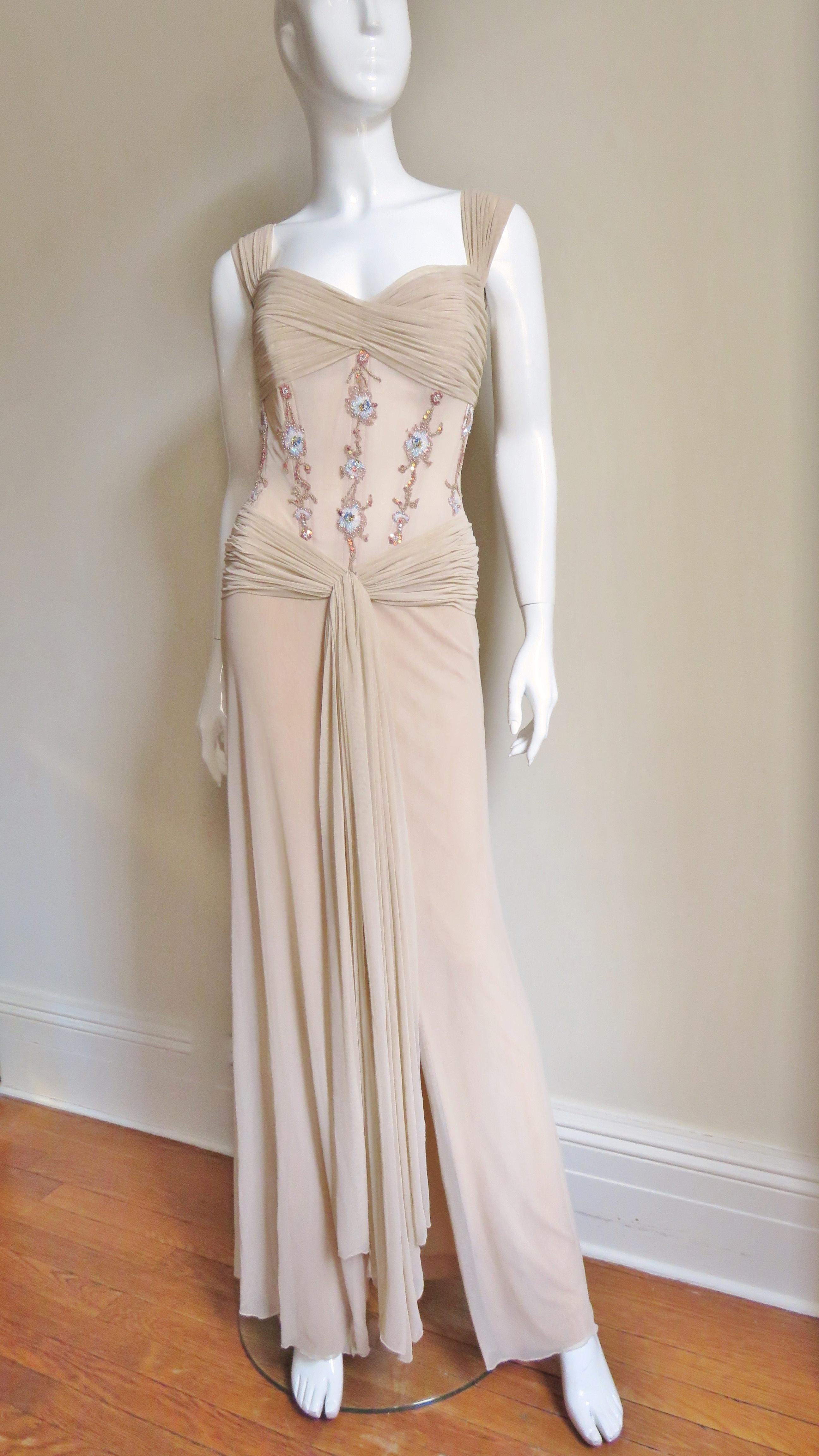 A fabulous beige silk gown from Vicky Tiel Couture.  It has a boned corset style bodice adorned with vertical lines of elaborately beaded flowers. There is a ruched panel across the bust and around the hips of the long A lined skirt. The dress is