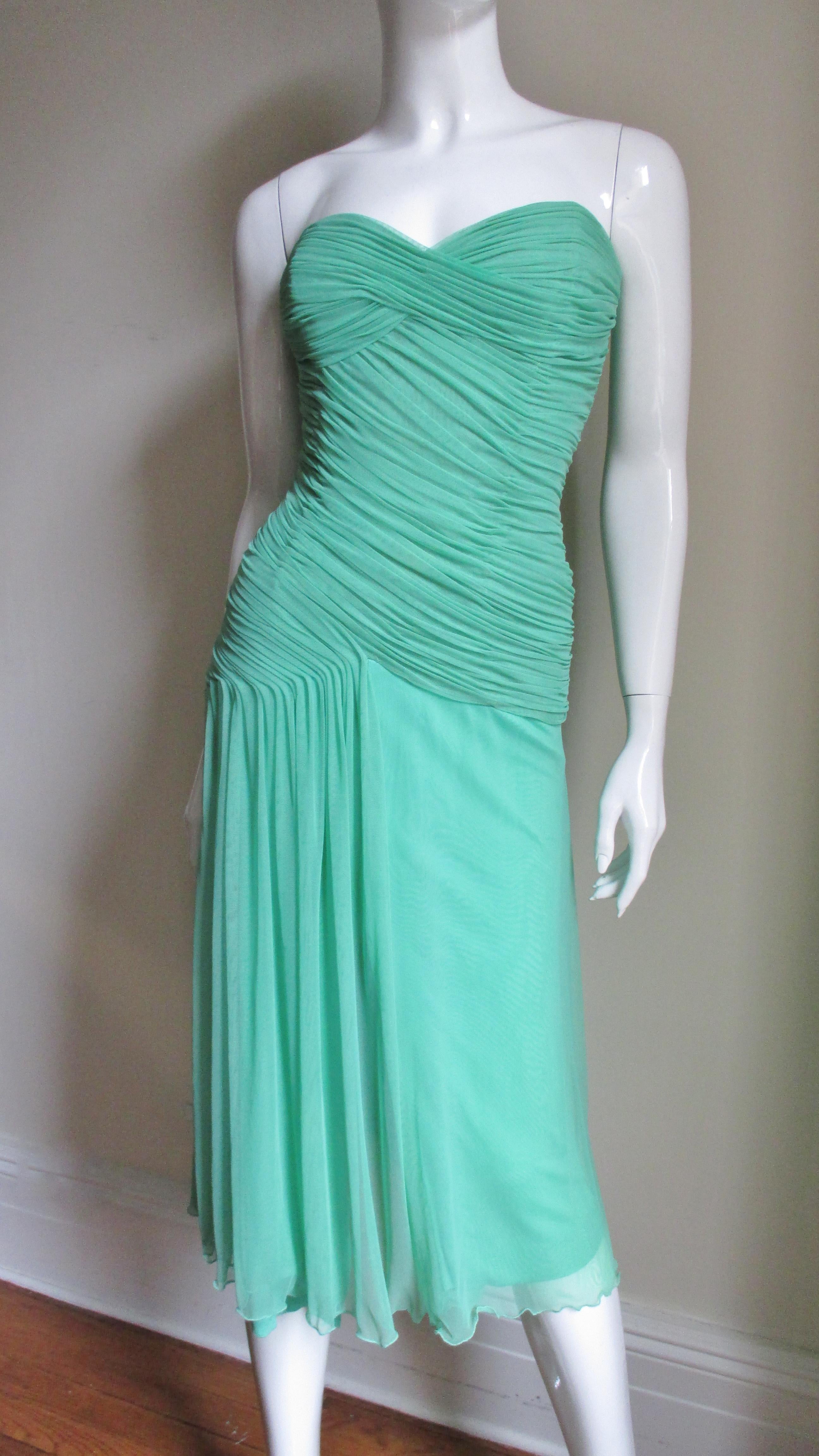 A fabulous stretch silk net dress from Vicky Tiel Couture in a beautiful shade of green. It has a boned strapless corset style bodice wrapped flatteringly with ruching crisscrossing the bust line, wrapping on an angle around the waist then draping