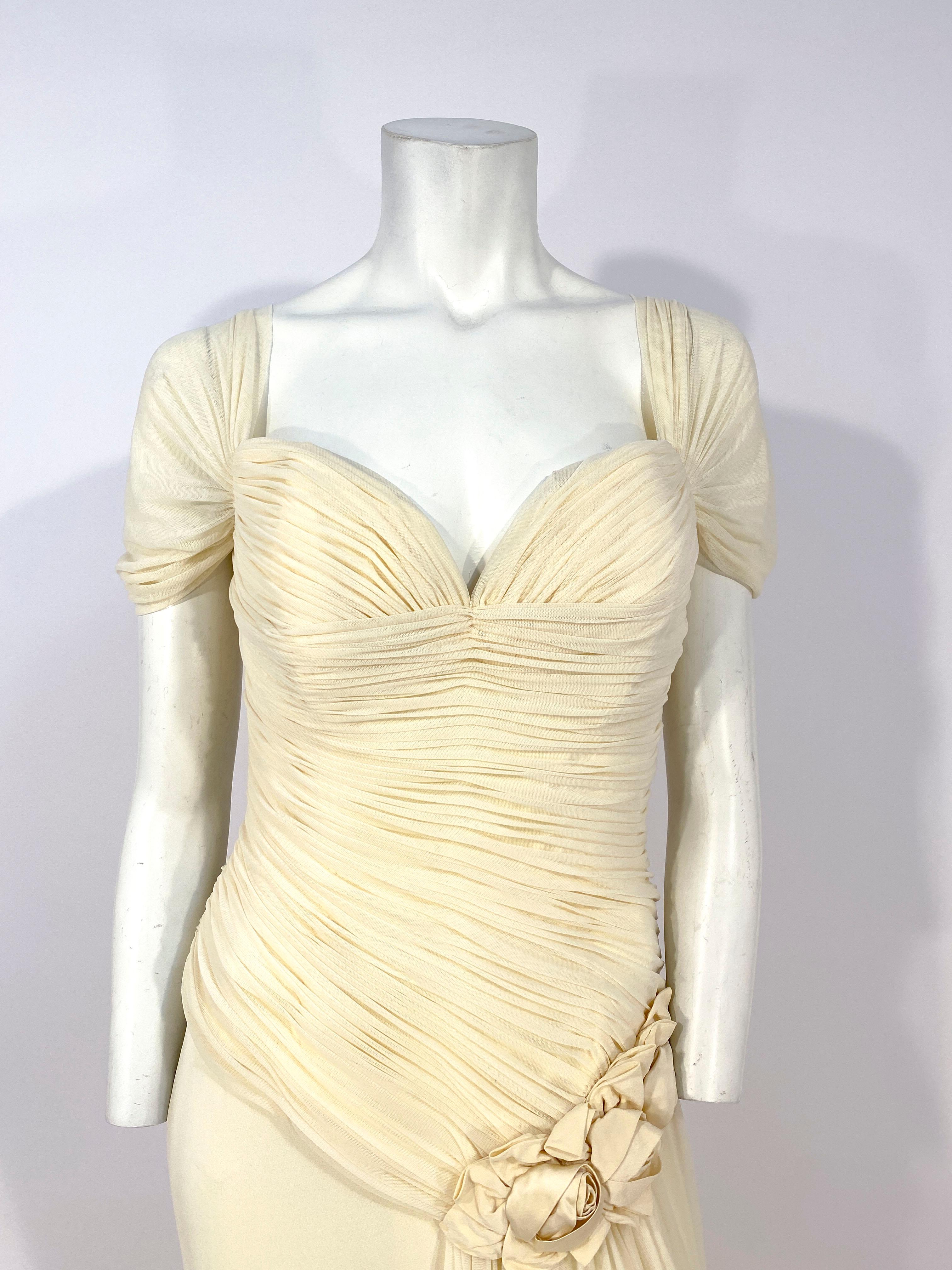 1990s ivory-colored full length evening gown made of silk tulle ruched along the entire bodice. The off-the-shoulder are drapes are attached to the bodice and the skirt has a large and high leg slit covered with a gathered flounce finished at the