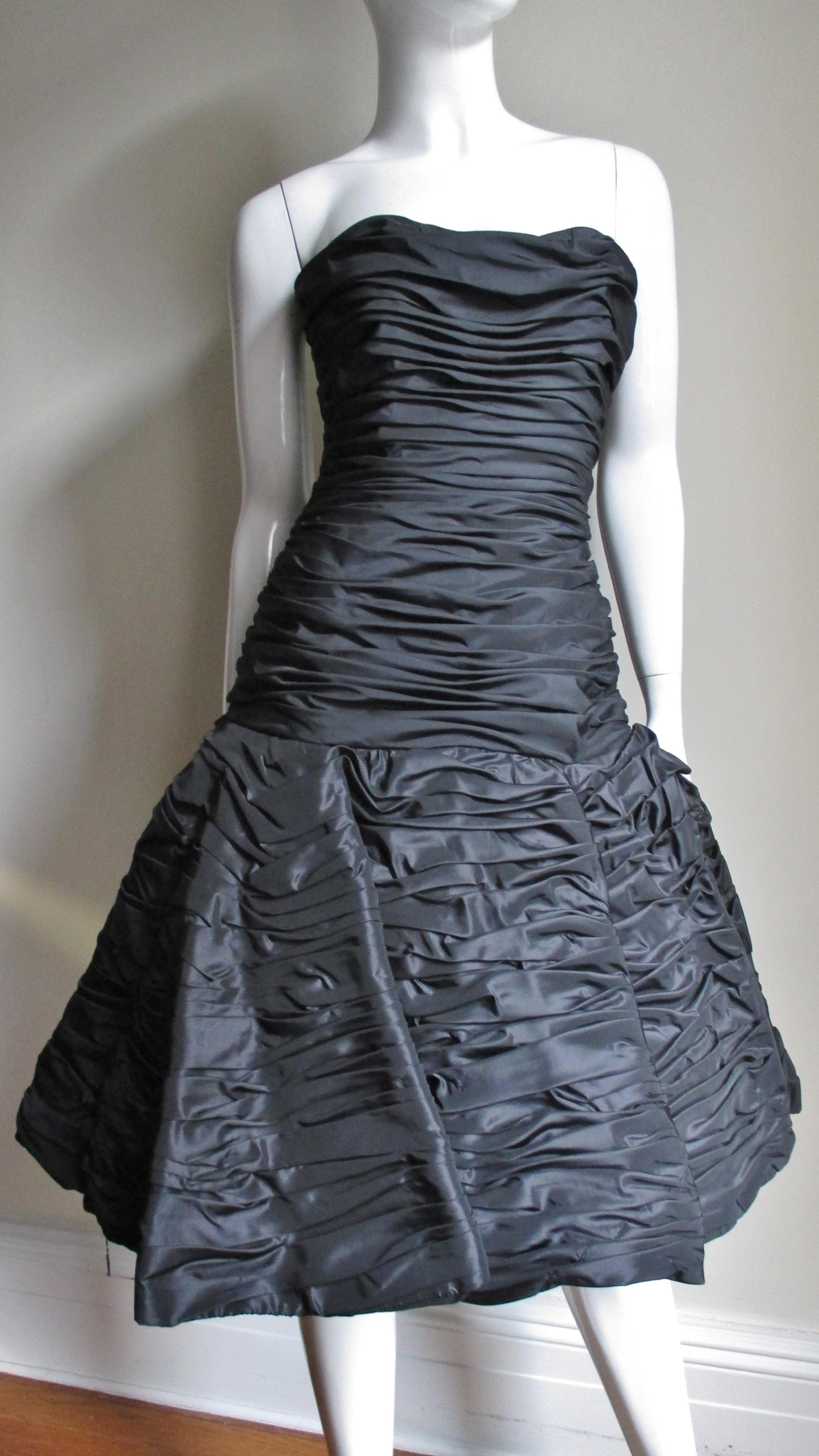 A beautiful black taffeta dress from Victor Costa. It has a strapless sweetheart neckline and a horizontally ruched bodice with vertical boning for support. The skirt is ruched, sculptural and full.  The dress has a back zipper and is fully