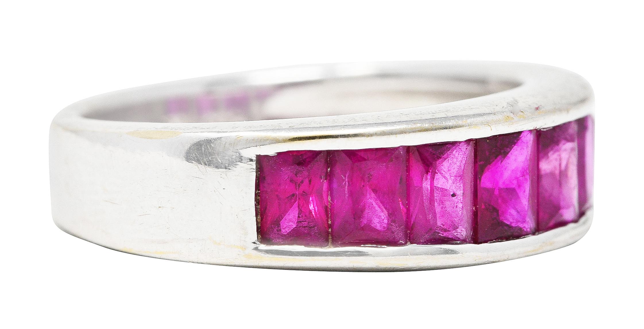 Band ring is channel set to front by eight scissor cut rubies - graduating in size. Weighing in total approximately 2.00 carats. Eye clean with very well matched purplish red color. Maker's marks and stamped 750 for 18 karat gold. Circa: 1990s. Ring