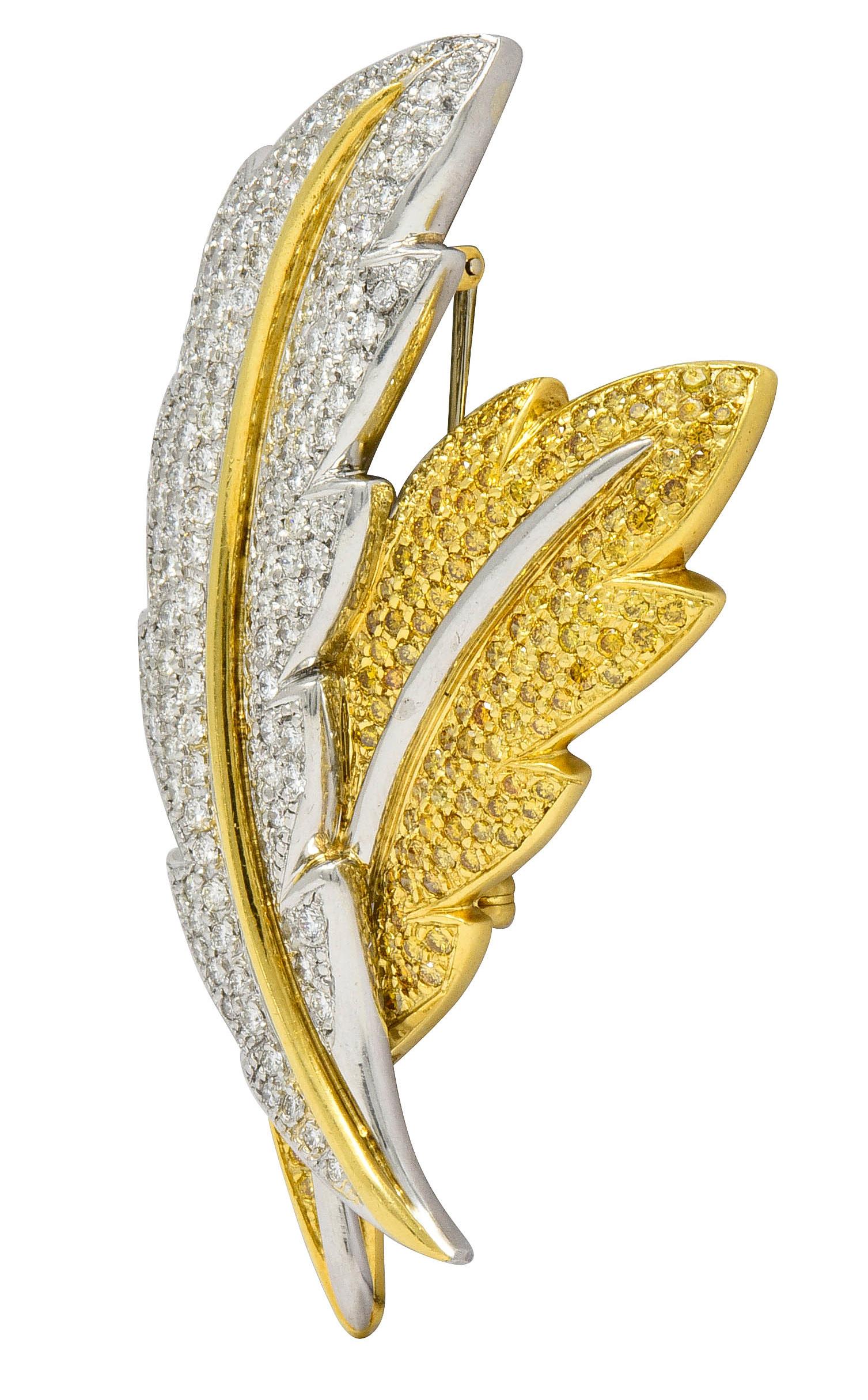 Brooch is designed as two stylized overlapping feathers with brightly polished stems of platinum and gold

Top feather is platinum and pavè set throughout by round brilliant cut diamonds weighing approximately 4.50 carats; G to I color with SI