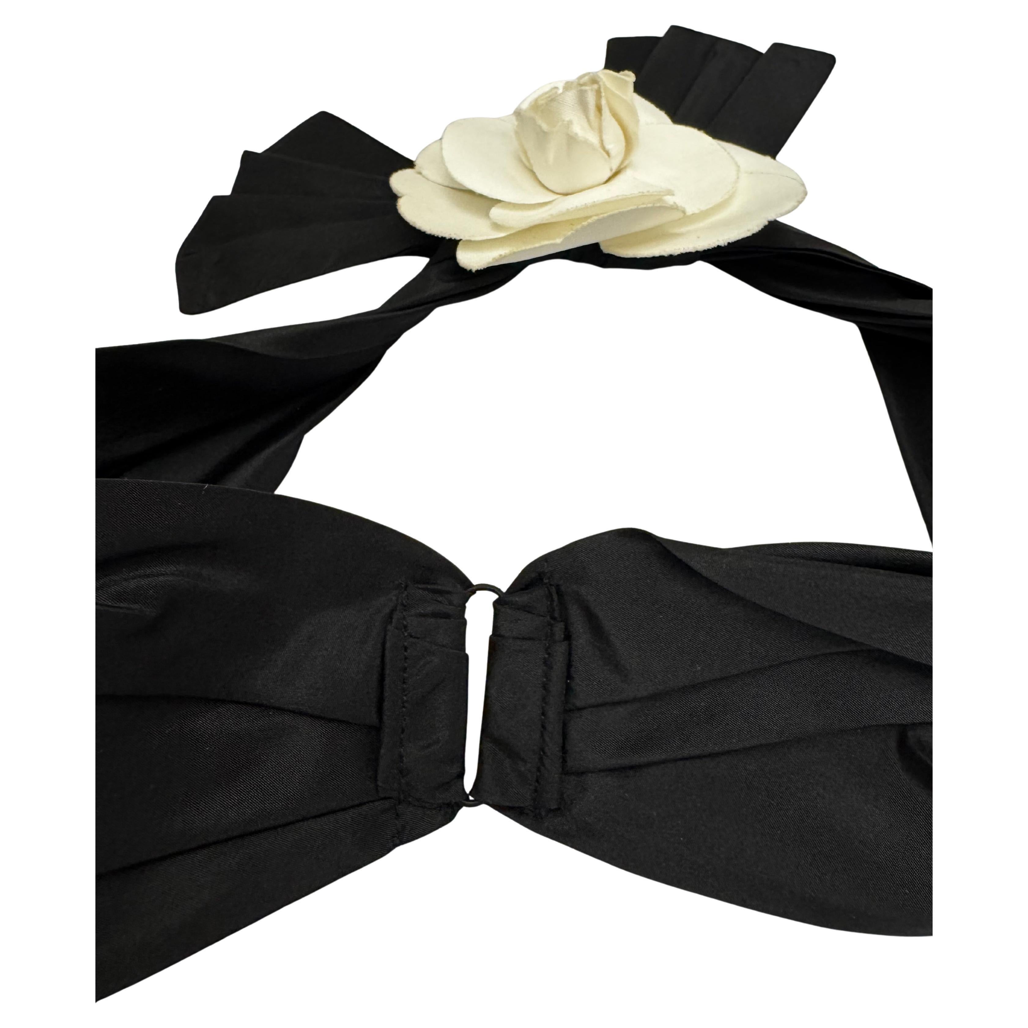 This vintage CHANEL camellia headband is crafted of black pleated fabric adorned with an off-white cotton camellia. The back has an elastic band to allow the headband to fit securely. Stamped CHANEL made in France. Circumference measures