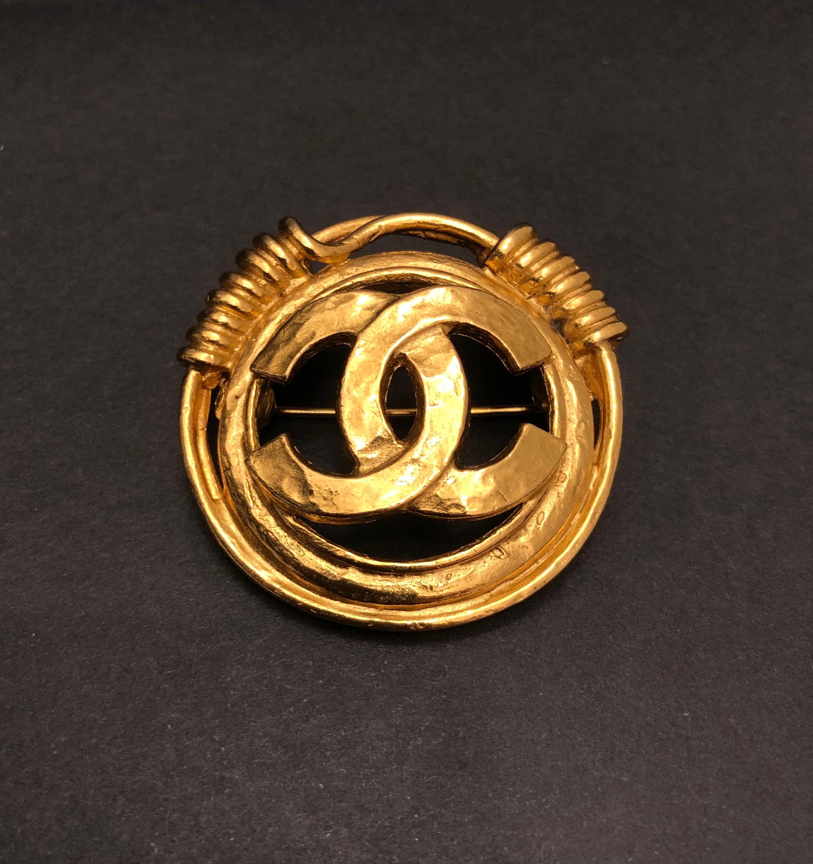 This vintage Chanel gold toned brooch is crafted of gold plated metal featuring a CC logo surrounded by a gold toned coiled ring. Stamped 94P made in France. Measures approximately 3.6 cm in diameter. Comes with box. 

Condition: Excellent vintage