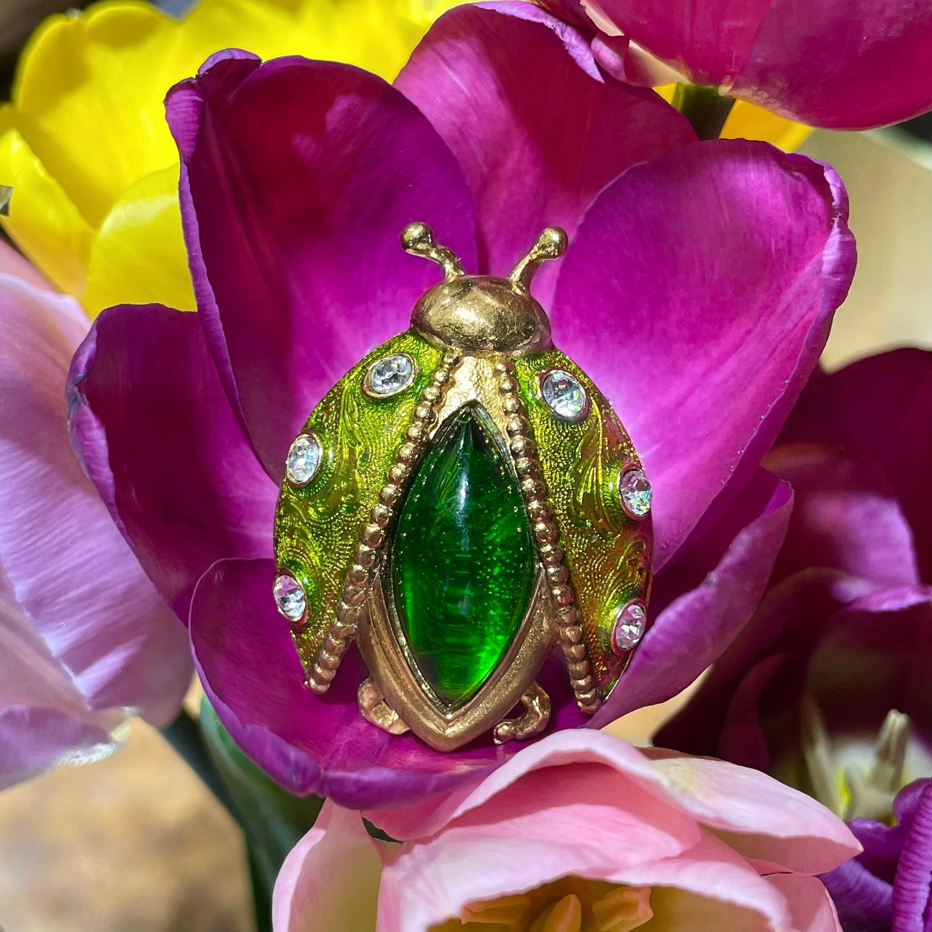 This is a lovely jewelled ladybug pin brooch designed by Christian Dior in 1990’s. The piece is gold plated. It is adorned with green enamel, clear rhinestones and almond cabochon green resin.

Signed: “Christian Dior. Parfums” (shown in