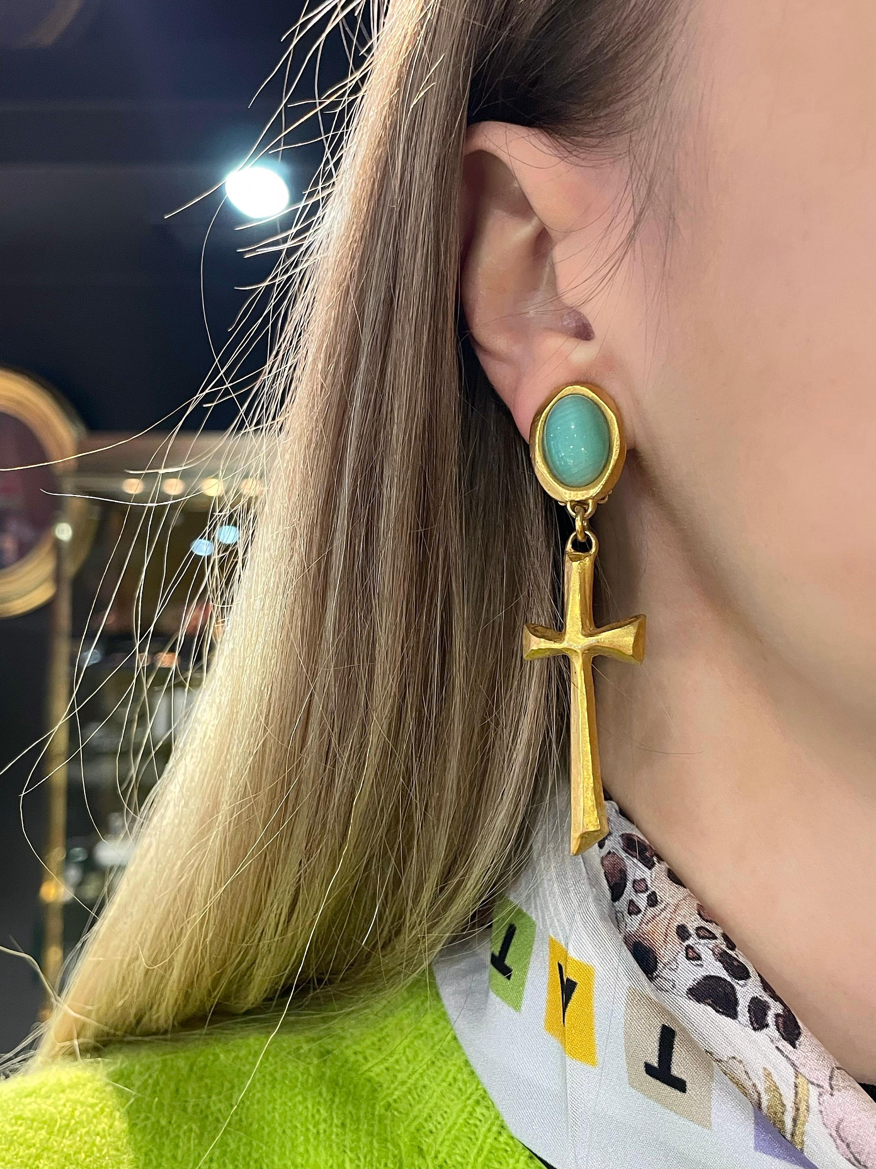 This is a pair of long cross clip on earrings designed by Christian Lacroix in 1990’s. 

The piece is crafted in base metal and is gold plated. It features turquoise colour glass cabochons. 

Signed: “Christian Lacroix - CL - Made in