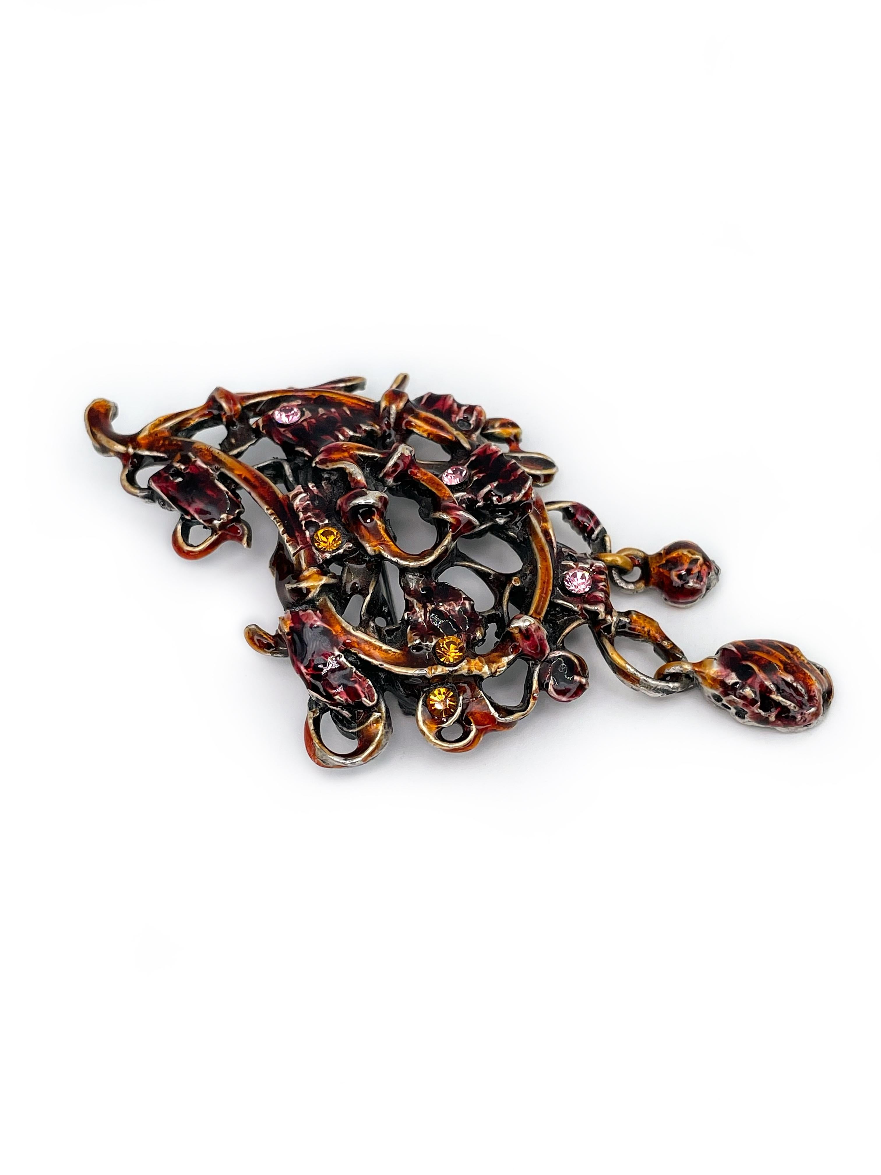This is an intricate openwork pin brooch designed by Christian Lacroix in 1990’s. Silvered metal is covered with red and orange enamel. The piece features tiny orange and pink rhinestones. It has  dangling charms. 

Signed: “Christian Lacroix - CL -