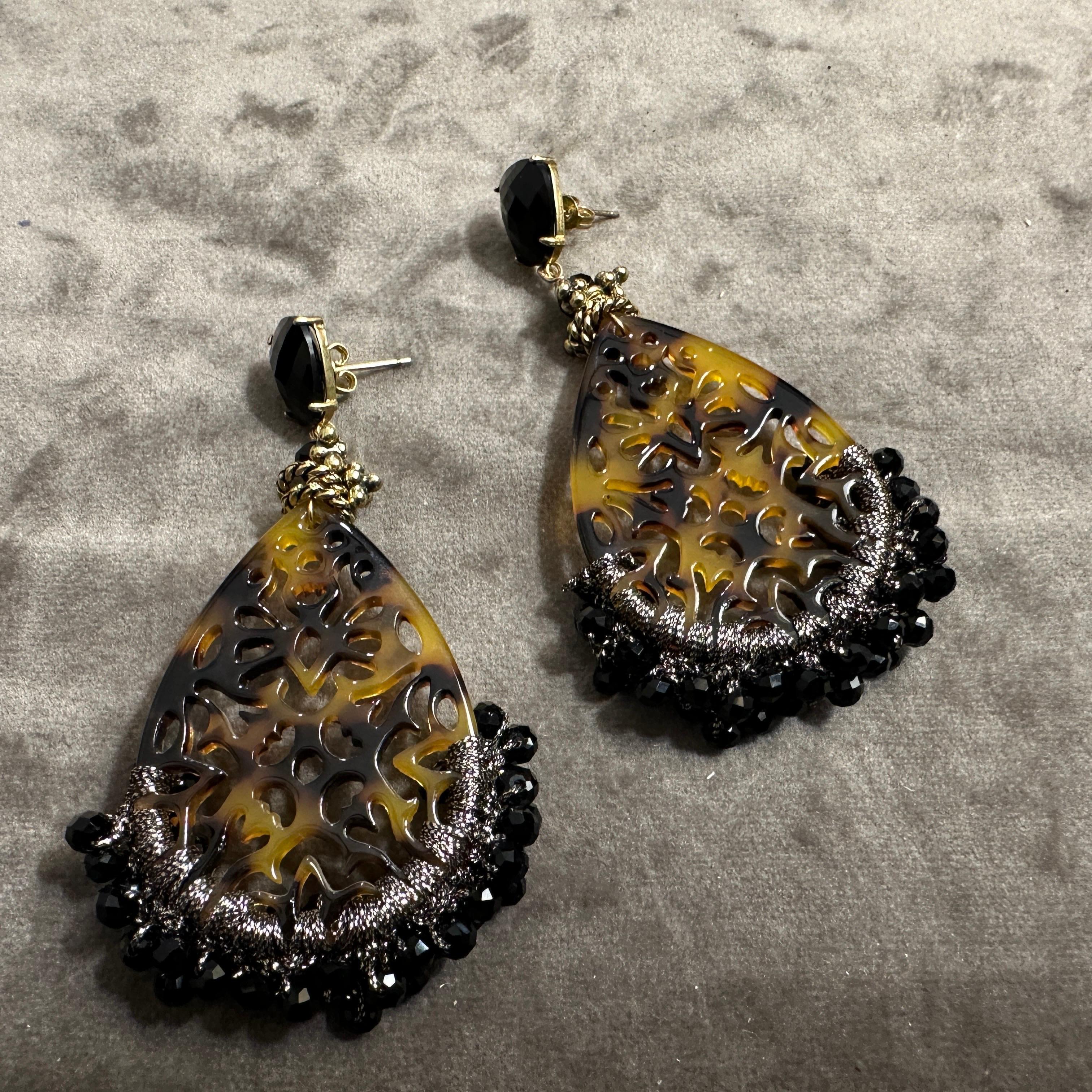 Ces boucles d'oreilles en forme de goutte d'eau sont une fusion captivante d'artisanat complexe et de design audacieux. Dotées de grands pendentifs en forme de goutte d'eau avec un motif de découpe orné, les boucles d'oreilles évoquent un sentiment