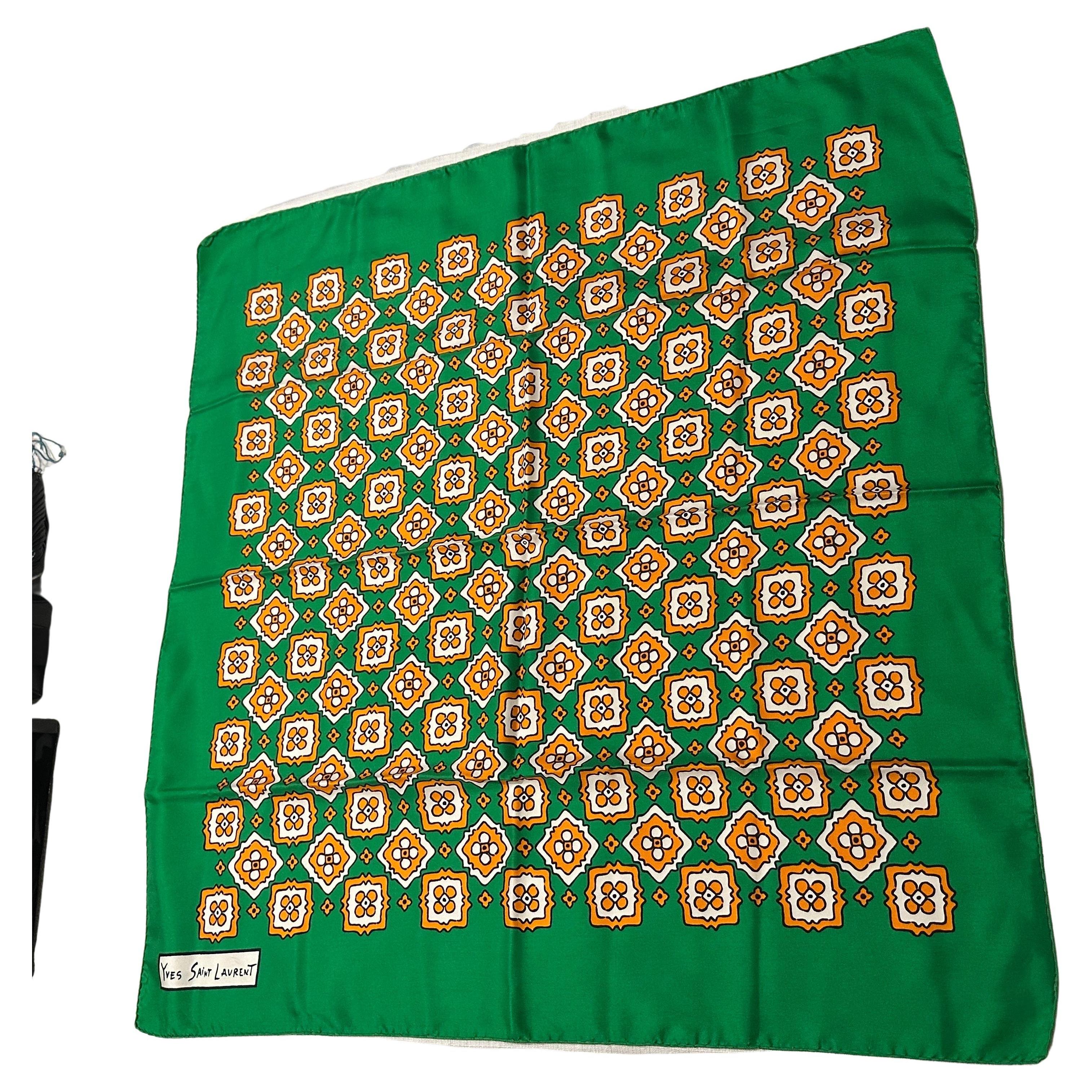 Embrace the bold elegance of the 1990s with this vintage silk carré scarf by Yves Saint Laurent. Featuring a vibrant green background, the design showcases a mesmerizing geometric floral motif in warm tones of yellow, orange, and white, arranged in