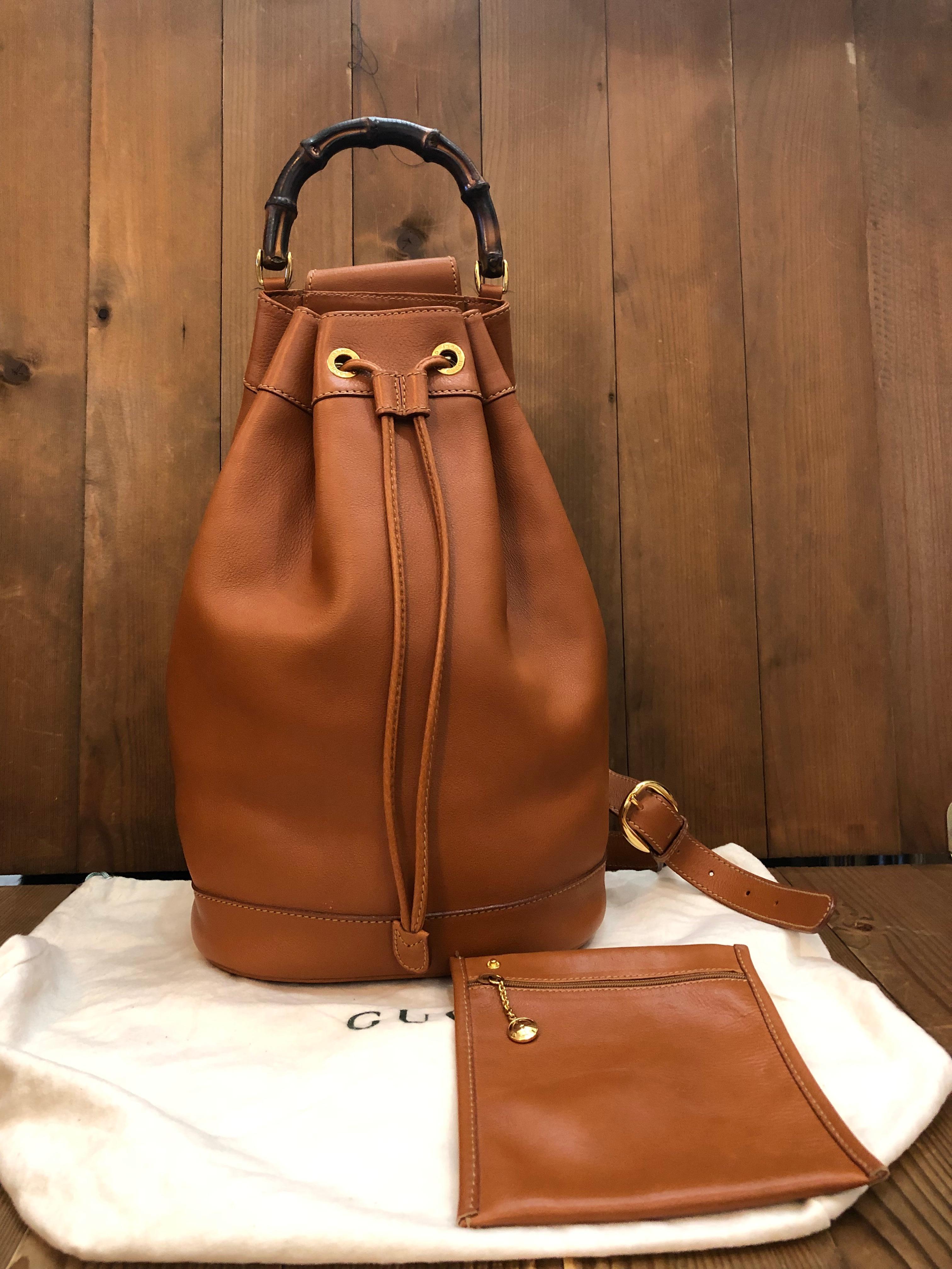This GUCCI bucket shoulder bag is crafted of soft smooth calfskin leather in caramel featuring gold toned hardware and a bamboo handle. Top drawstring closure opens to unlined interior featuring a detachable zippered pouch of the same leather.