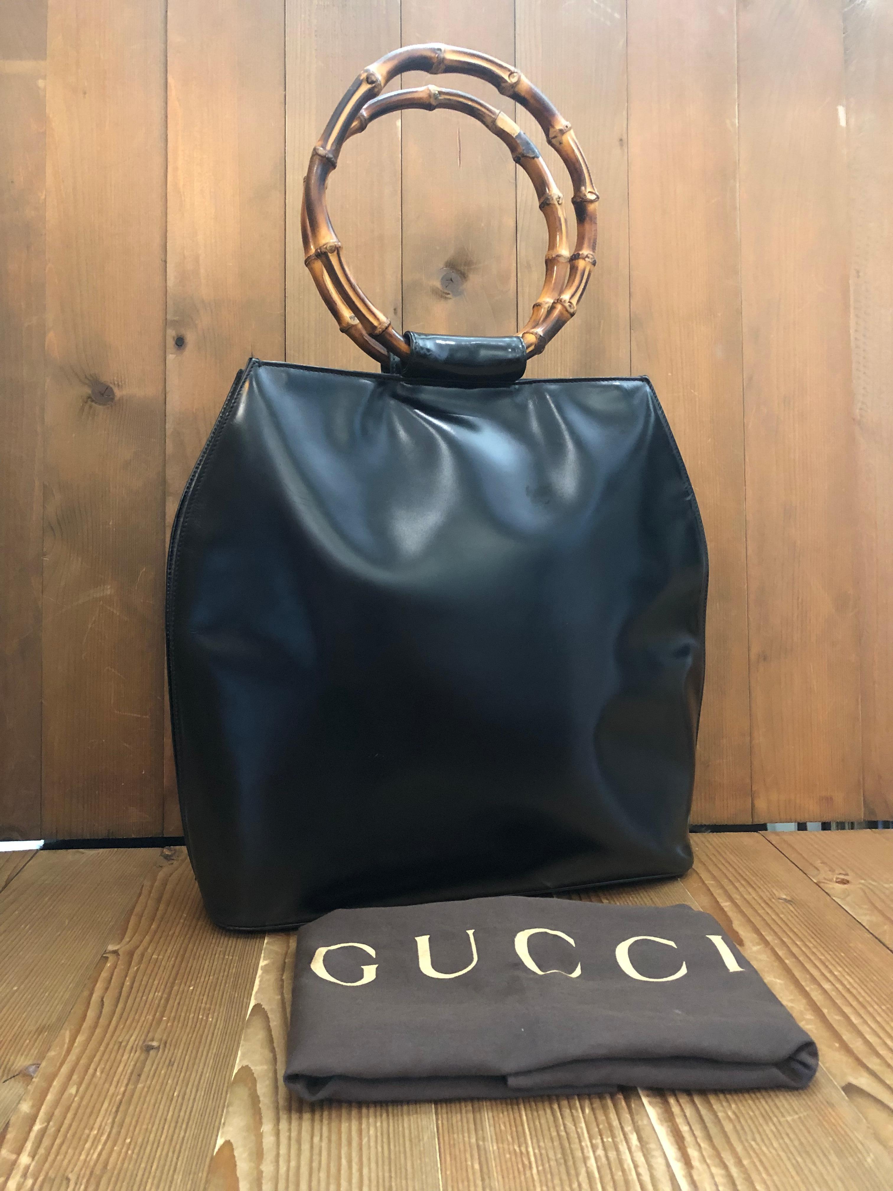 This vintage GUCCI top handle shoulder tote bag is crafted of polished calfskin leather in black featuring two massive bamboo ring handles. Top magnetic snap closure opens to a new interior in black featuring a zippered pocket. Made in Italy.