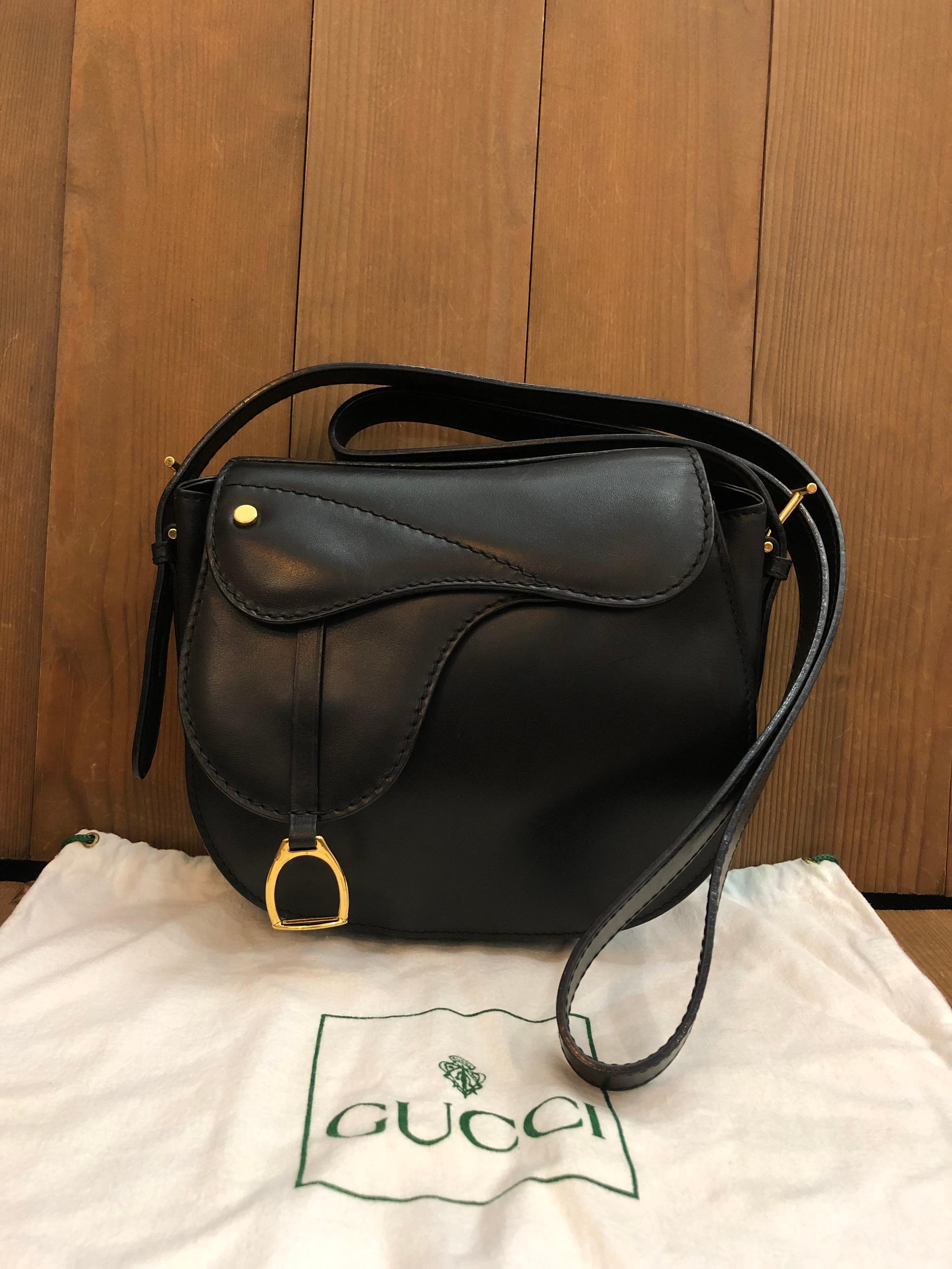 This vintage GUCCI mini saddle bag is crafted of smooth calfskin leather in black featuring gold toned hardware and equestrian accent. Front magnetic snap closure opens to a coated interior which has been professionally cleaned featuring a zippered