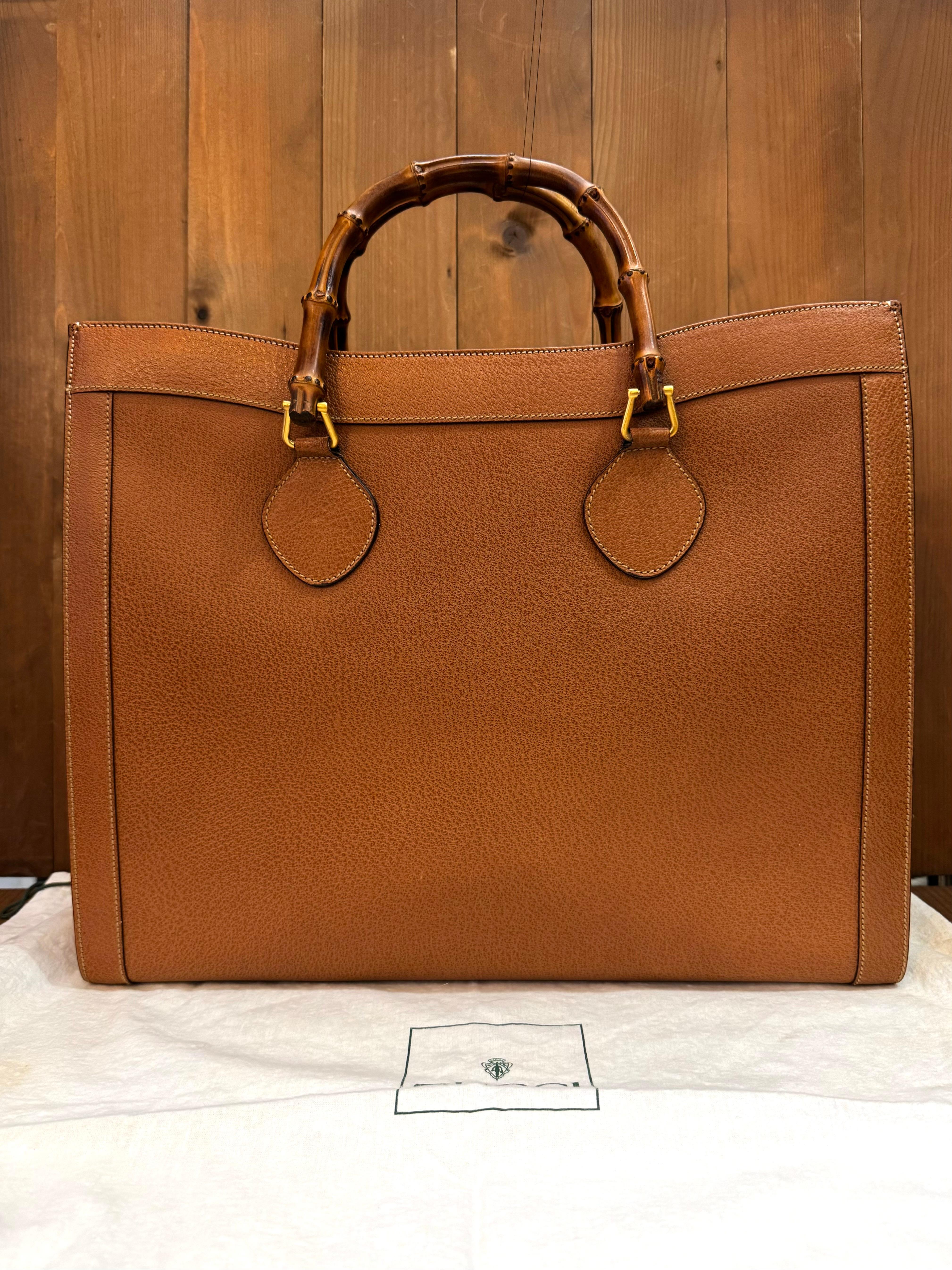 This large vintage GUCCI Diana bamboo tote is crafted of pigskin leather in brown featuring gold toned hardware and sturdy bamboo handles. Top magnetic snap closure opens to a new interior in beige featuring two main compartments/one zippered