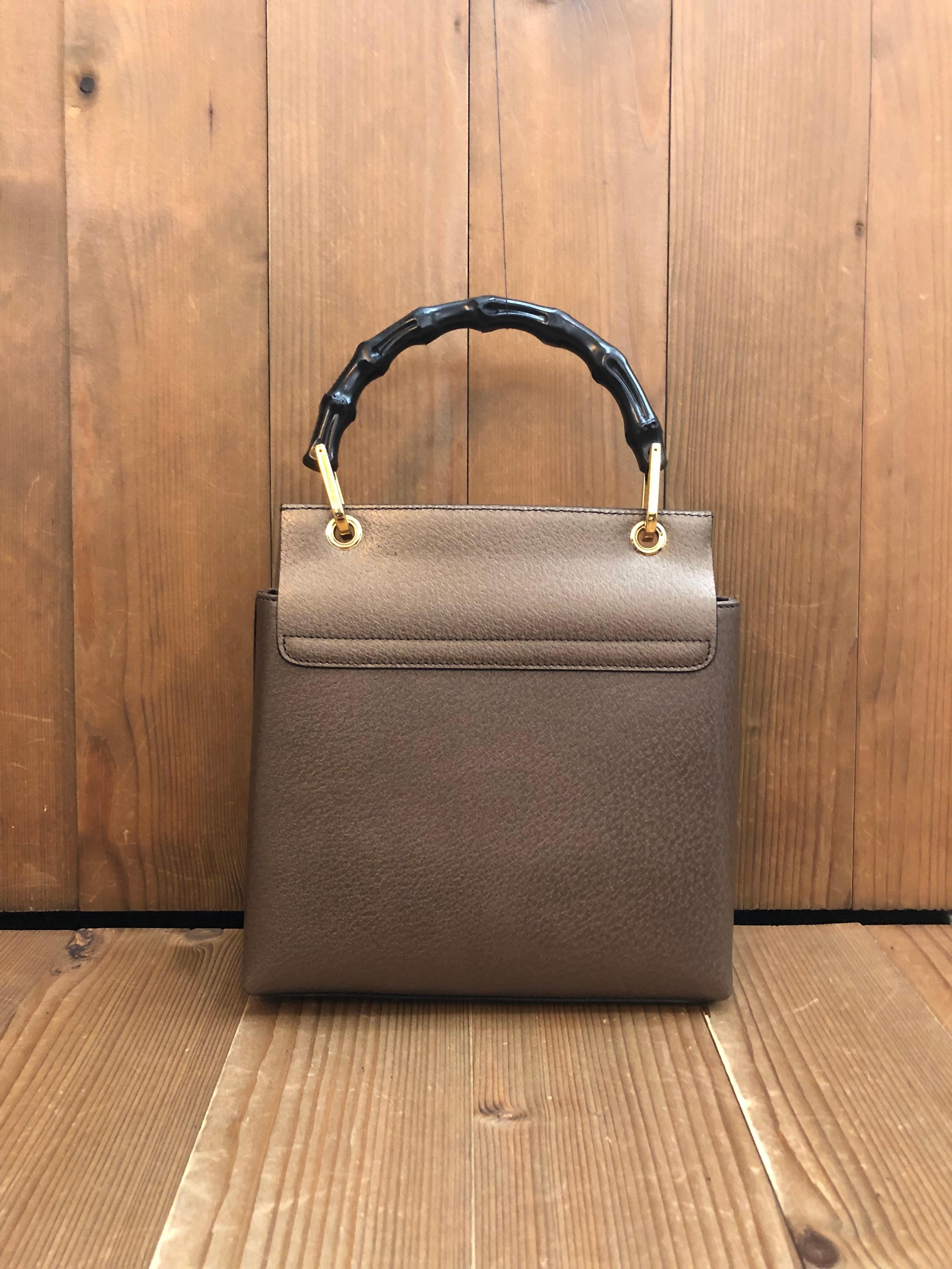 This vintage GUCCI mini bamboo top handle bag is crafted of pigskin leather in metallic brown featuring gold toned hardware and a black bamboo handle. Front flap magnetic snap closure opens to a luxurious nubuck leather interior in brown featuring a