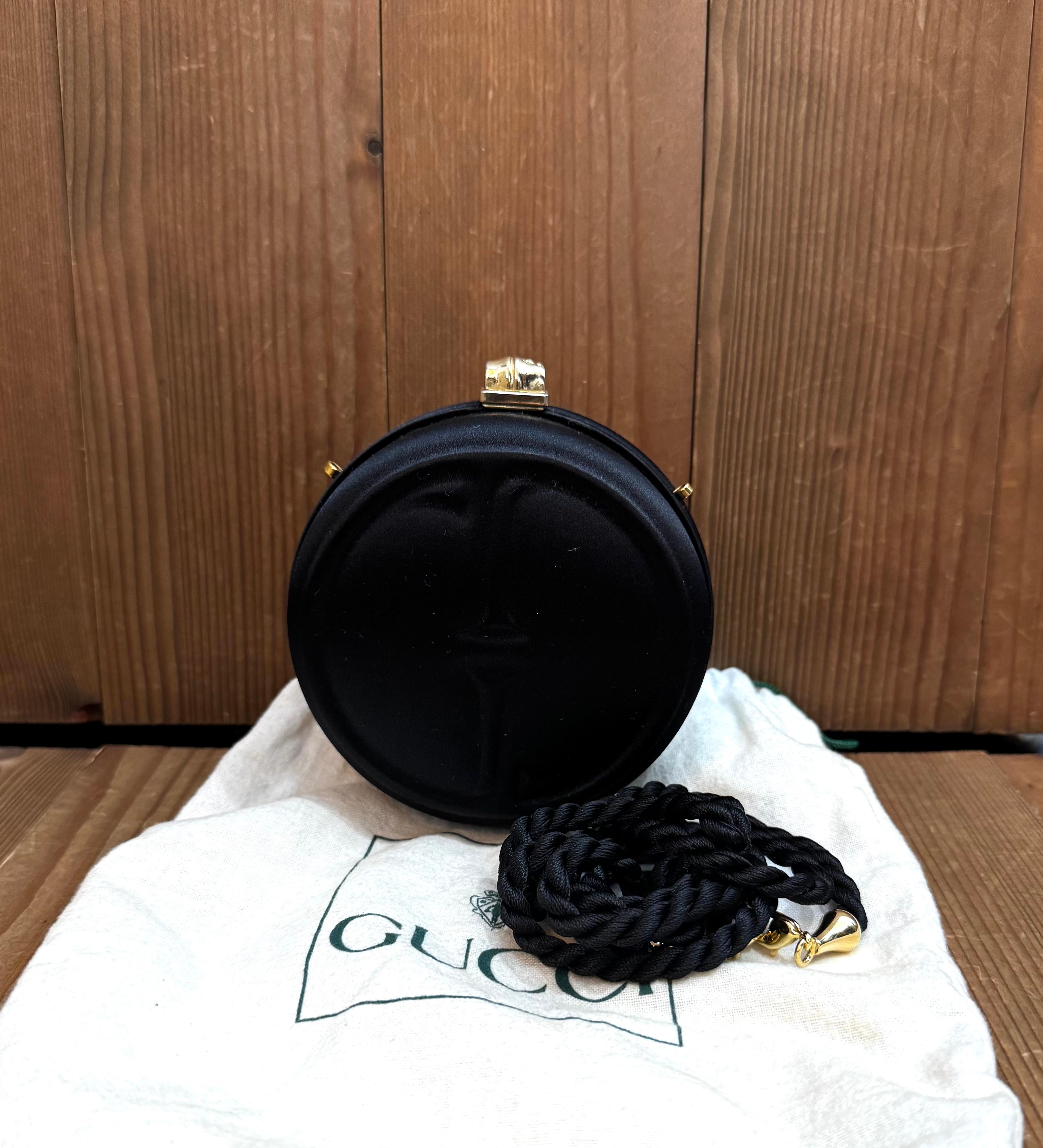 This vintage GUCCI micro evening box clutch bag is crafted of black satin featuring a massive GG impression on the front and a gold toned bamboo clasp. Top bamboo kiss-clasp closure opens to a red satin interior. This vintage piece also features a