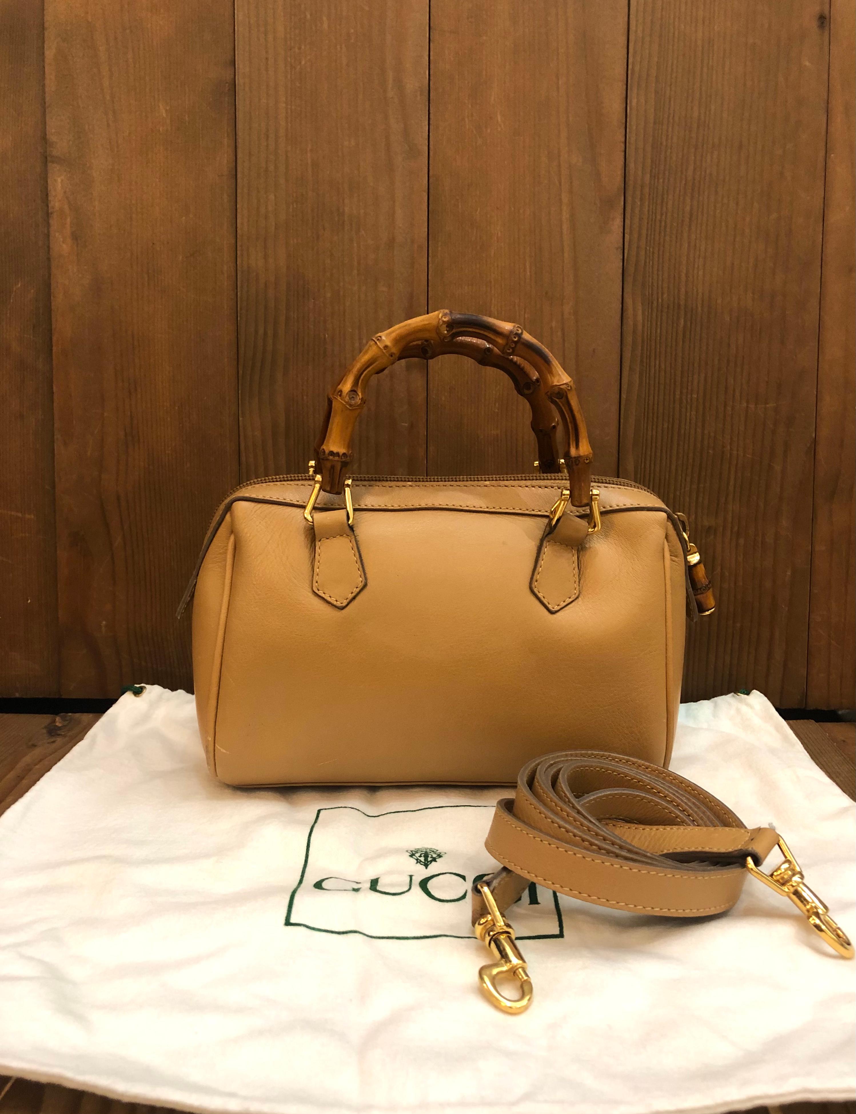 This 1990s vintage GUCCI mini two-way boston crossbody handbag is crafted of smooth calfskin leather in beige featuring gold toned hardware and bamboo handles. Top zipper closure opens to new interior in beige. This mini Gucci also features a