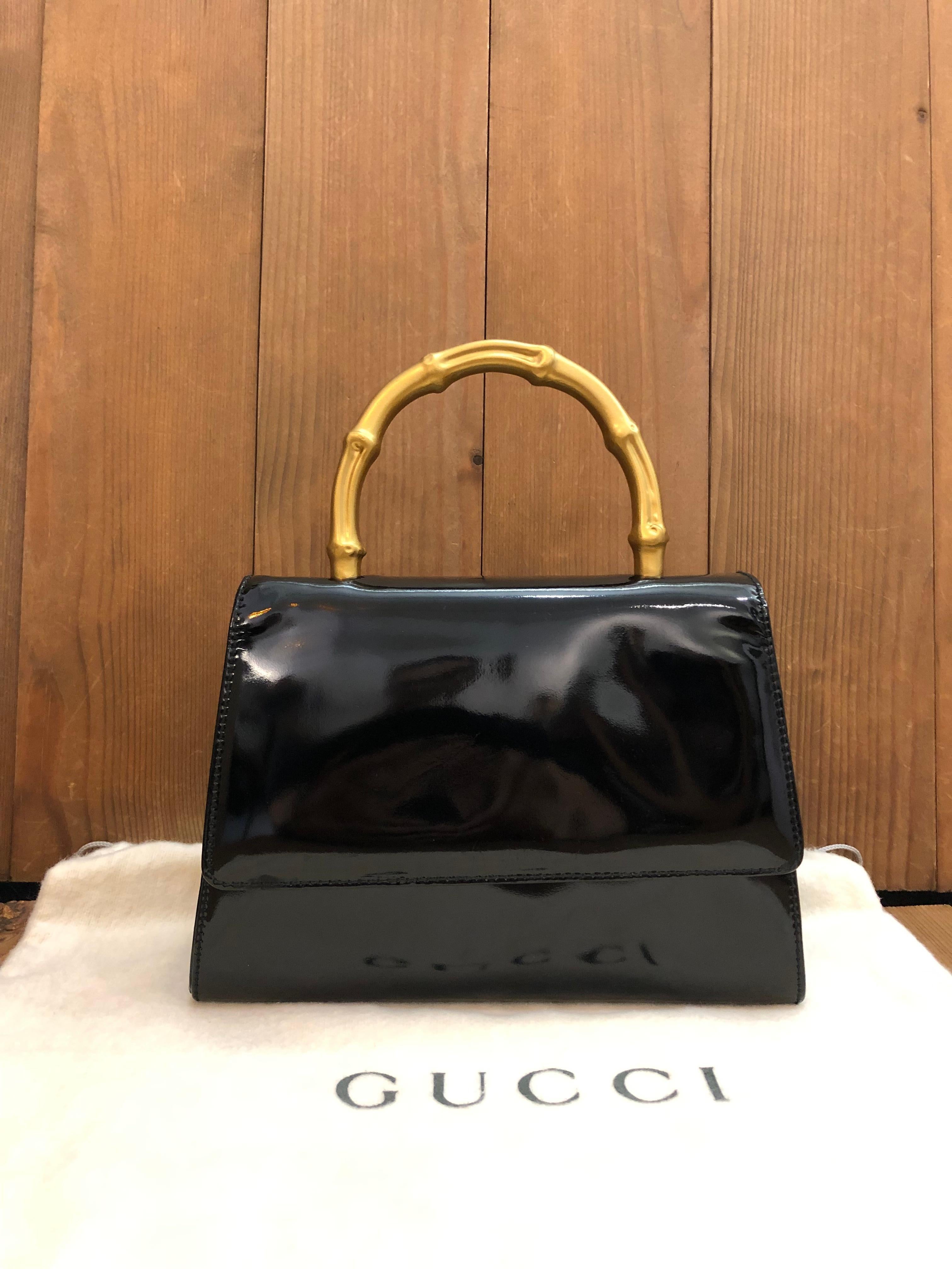 This exquisite 1990s vintage GUCCI mini handbag is crafted of patent leather in black featuring a gold toned bamboo ring handle. Front flap magnetic snap closure opens to a suede/silk satin interior featuring a patch pocket. Made in Italy. Measures