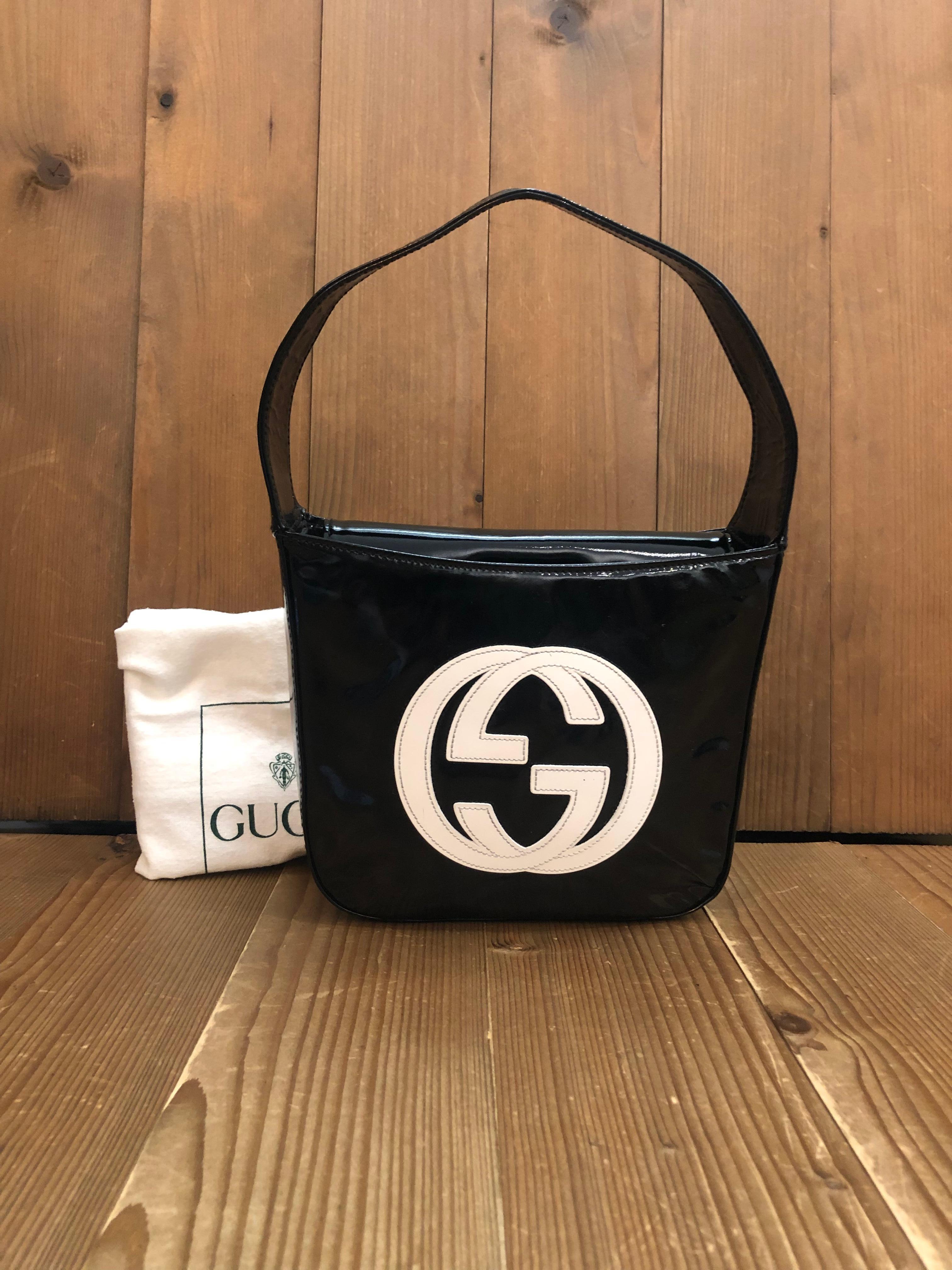 This vintage GUCCI Mini Hobo Handbag is crafted of patent leather in black featuring a massive white GG interlock logo at the front. Top flap magnetic snap closure opens to a coated interior which has been professionally cleaned featuring a patch