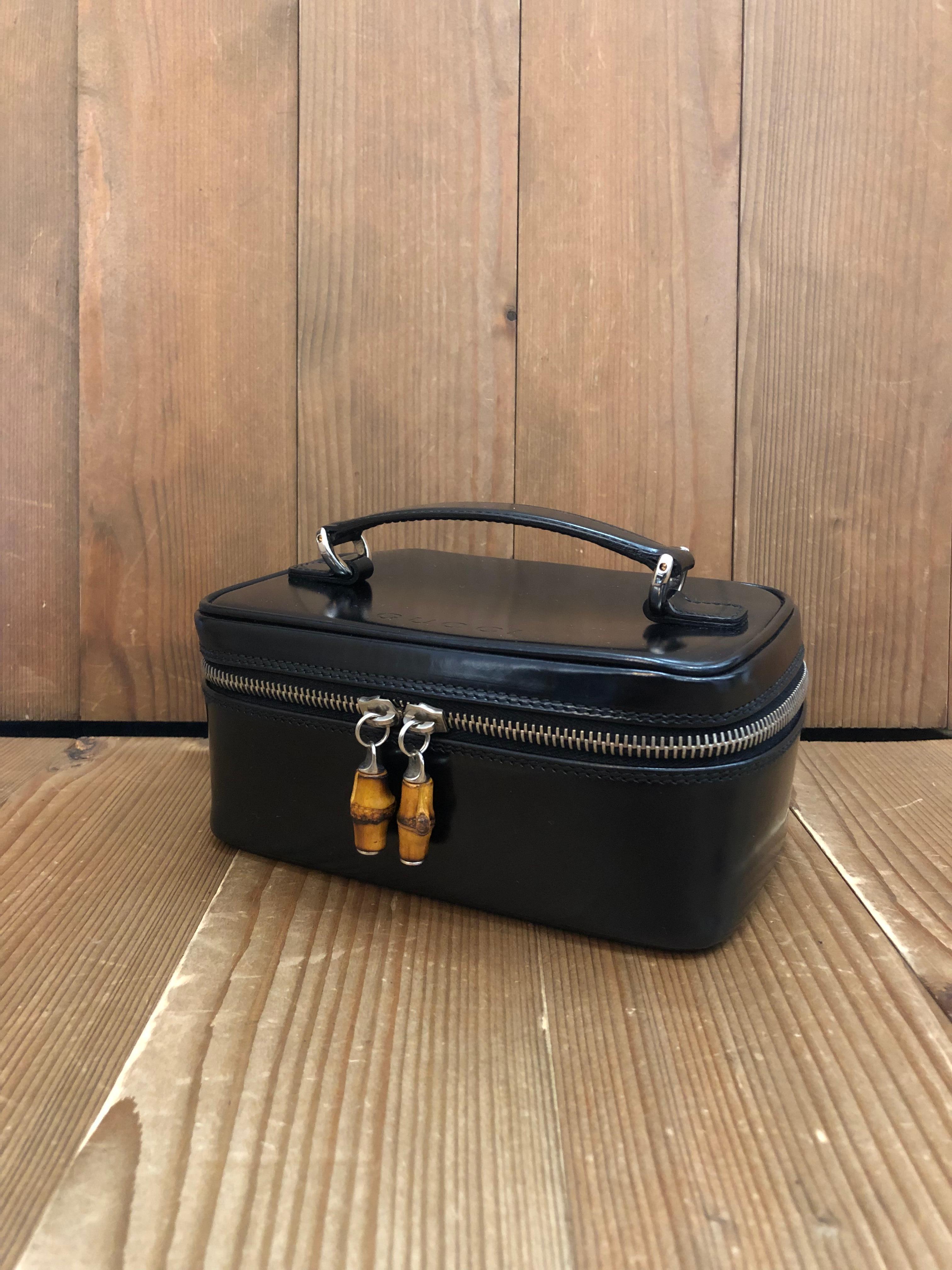 This vintage GUCCI mini vanity case handbag is crafted of polished calfskin leather in black featuring silver toned hardware and bamboo zipper pulls. Zip-around closure opens to a coated interior which has been cleaned. Made in Italy. Measures
