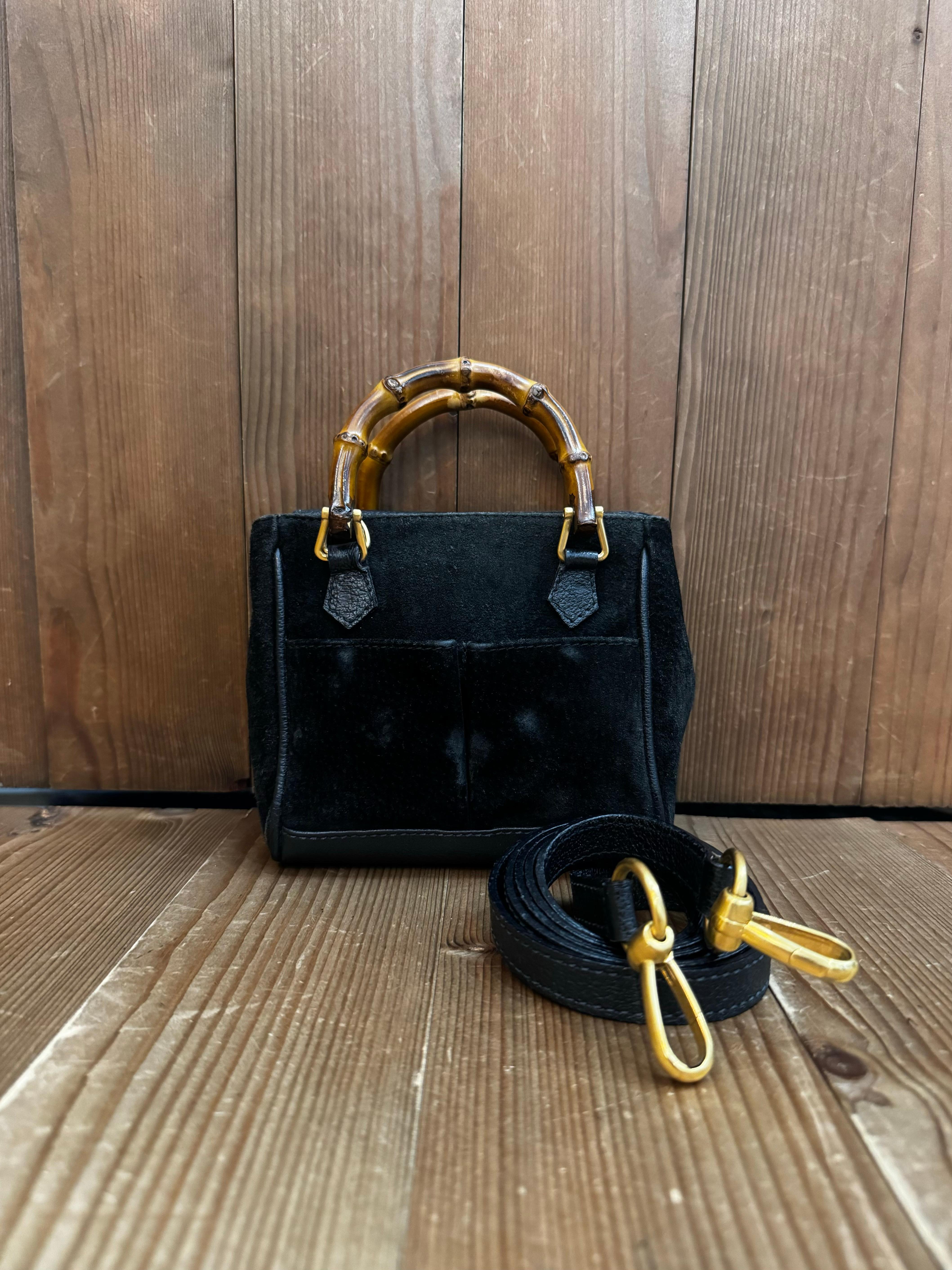 This vintage GUCCI mini 2-way bamboo crossbody bag is crafted of nubuck and pigskins leather in black featuring matt gold toned hardware and mini bamboo handles. The front of this bag features two open pockets lined with diamanté jacquard. Top