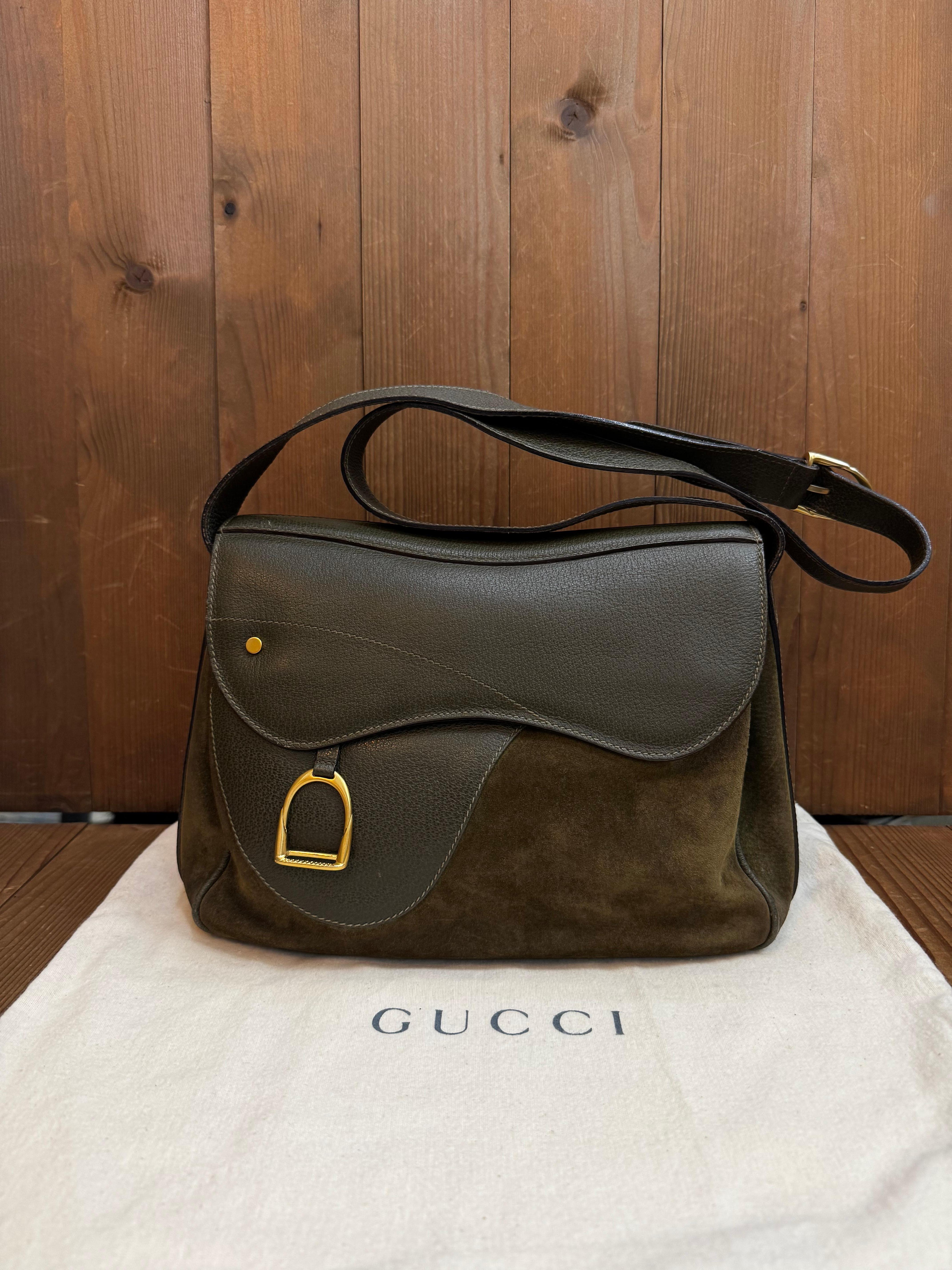 Cette sacoche vintage GUCCI est réalisée en nubuck et en cuir de porc vert foncé, avec des accessoires dorés mats. Le rabat avant à double fermeture magnétique, orné d'un charme d'étrier, s'ouvre sur un intérieur en jacquard vert diamanté, doté de