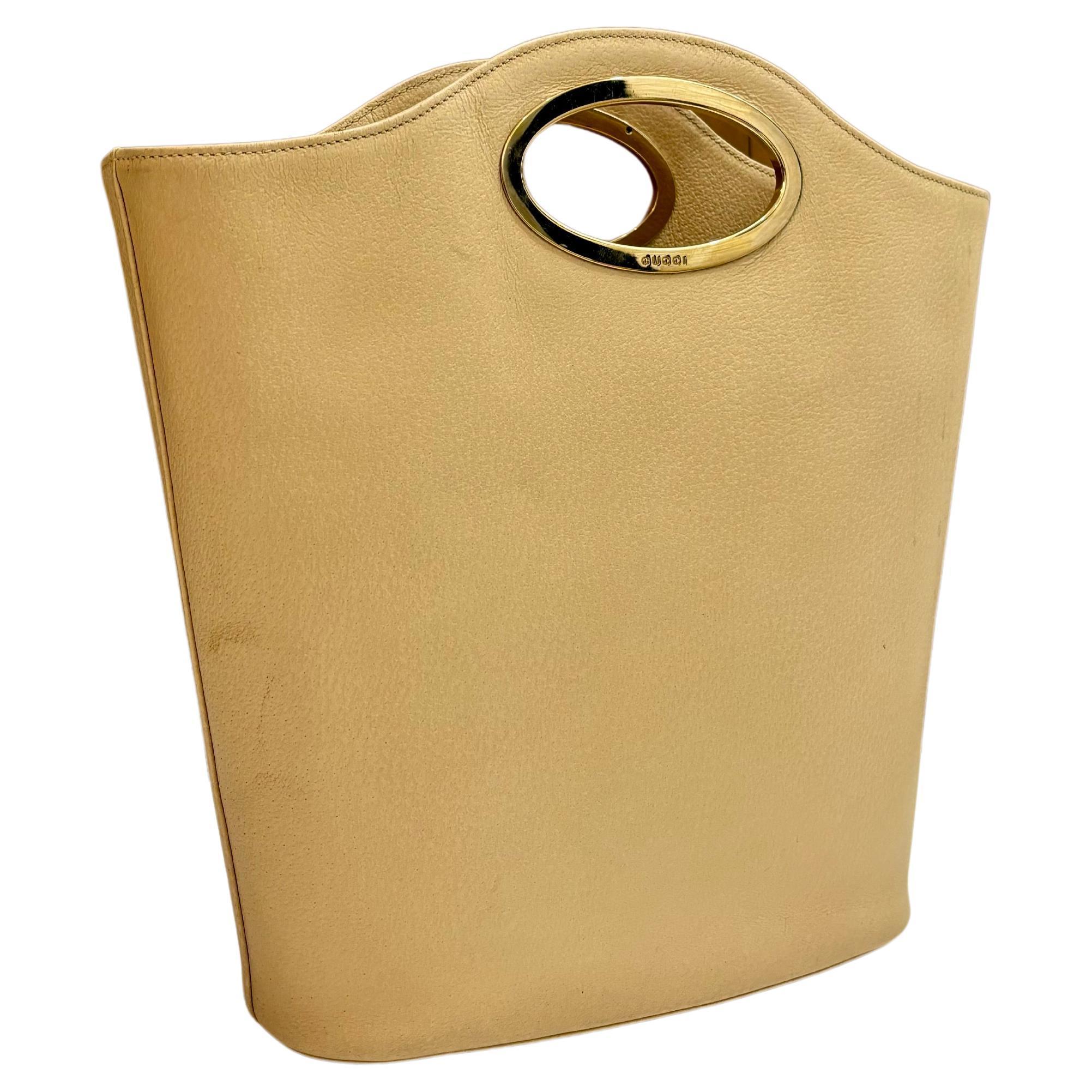 This vintage GUCCI book tote bag is crafted of pigskin leather in beige featuring gold toned hardware. Wide top opens to a new beige interior featuring one main compartment with one zippered pocket in the middle. Made in Italy. Measures