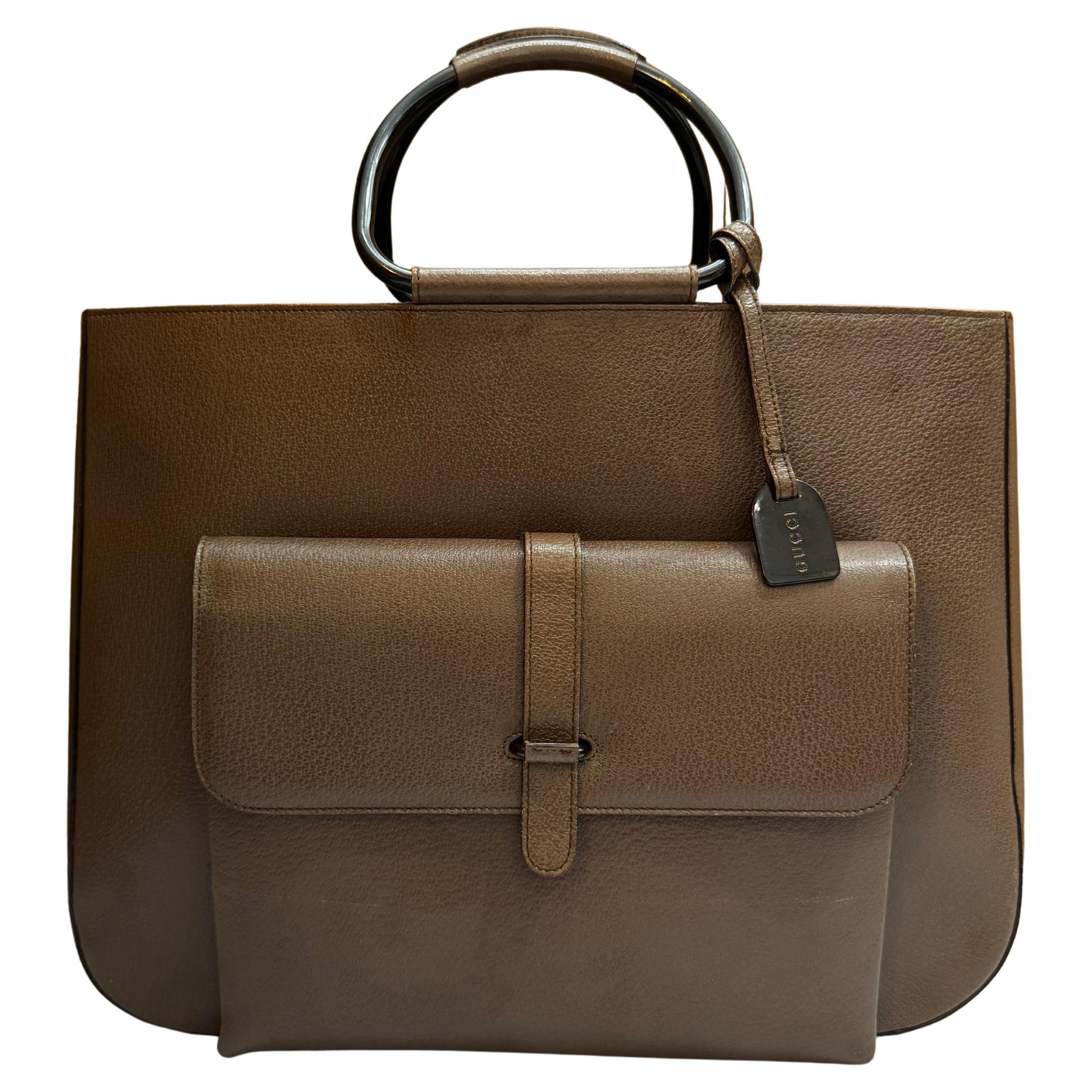This vintage GUCCI large tote bag is crafted of pigskin leather in brown featuring black enameled hardware and metallic rolled leather handles. Top flap magnetic snap closure opens to a coated interior which has been professionally cleaned featuring