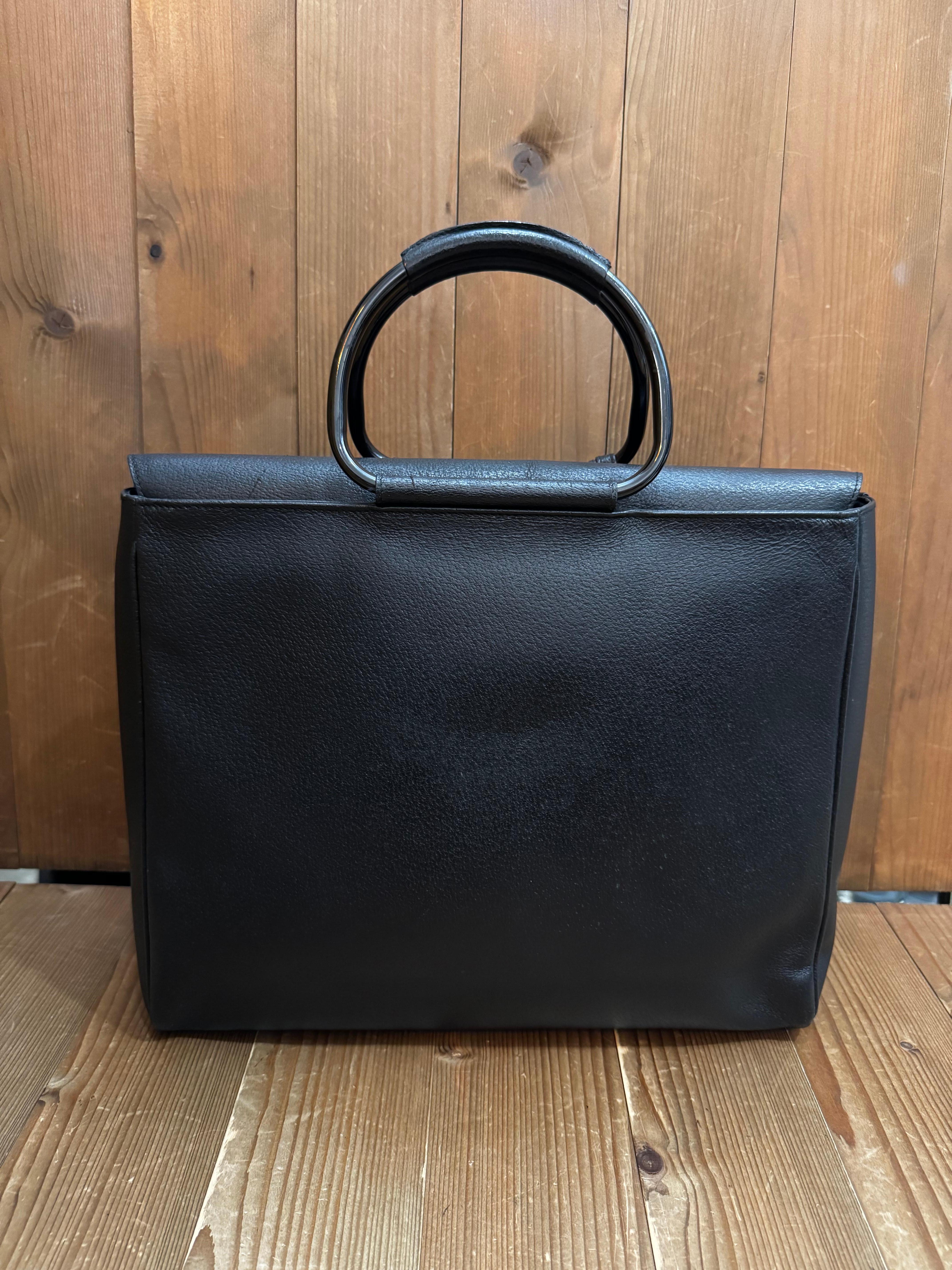 This vintage GUCCI large tote bag is crafted of pigskin leather in black featuring black enameled hardware and metallic rolled leather handles. Top flap magnetic snap closure opens to a coated interior which has been professionally cleaned featuring