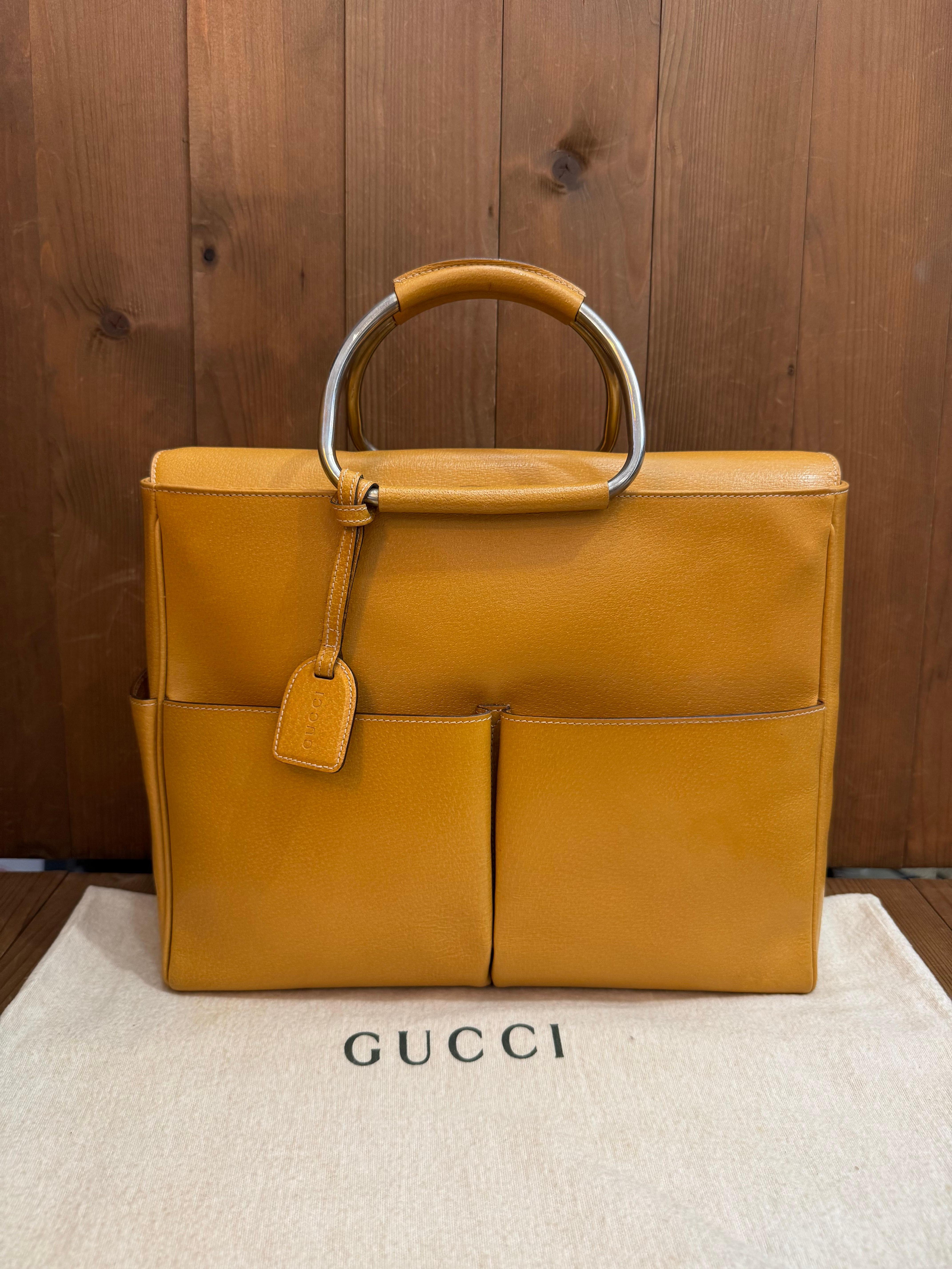 This vintage GUCCI tote bag is crafted of pigskin leather in mustard yellow featuring silver toned hardware and metallic rolled leather handles. Top flap magnetic snap closure opens to a coated interior which has been professionally cleaned