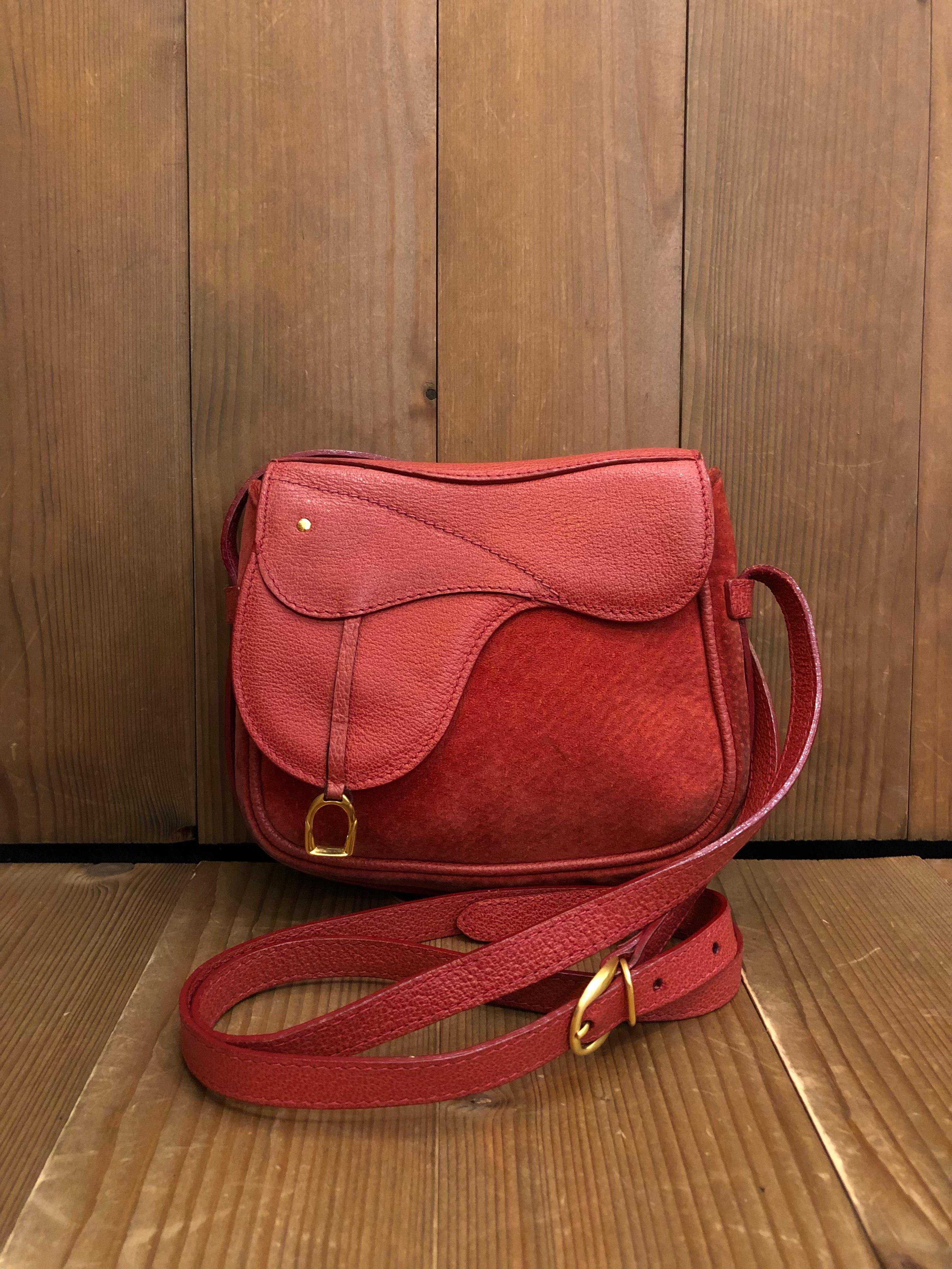 This vintage GUCCI mini saddle bag is crafted of suede and pigskin leather in red decorated with equestrian accent. This bag features a detachable crossbody strap of the same leather and leather loops at the back for securing on a belt to use it as