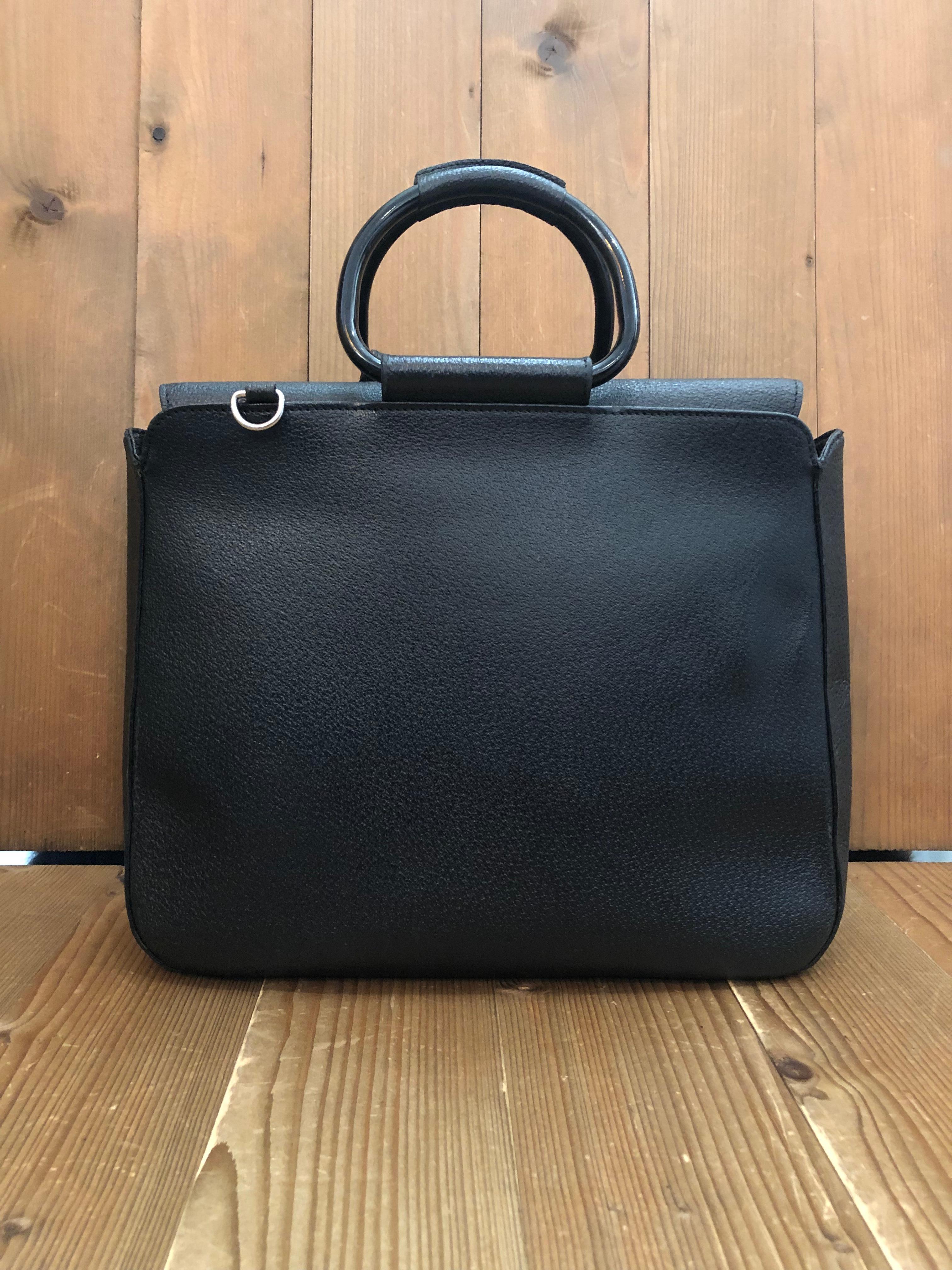 This vintage GUCCI shoulder bag is crafted of pigskin leather in black featuring silver toned hardware and rolled leather metallic handles. Top magnetic snap closure opens to a new coated interior which has been cleaned featuring a zippered pocket.