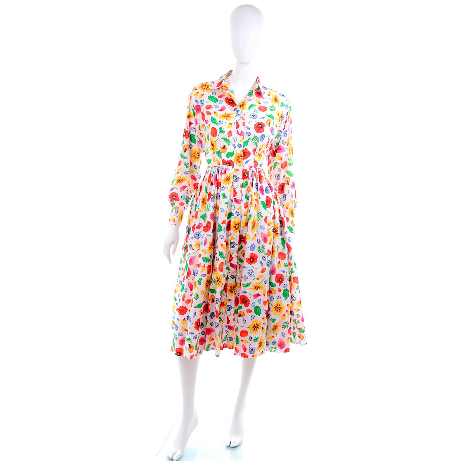 This is a pretty vintage 1990's Kenzo long sleeved cotton dress in a white, yellow, green, blue and red floral cotton print. This dress is beautifully made with a fitted waist, gathered full skirt, side slit pockets, and long sleeves. The shirtwaist