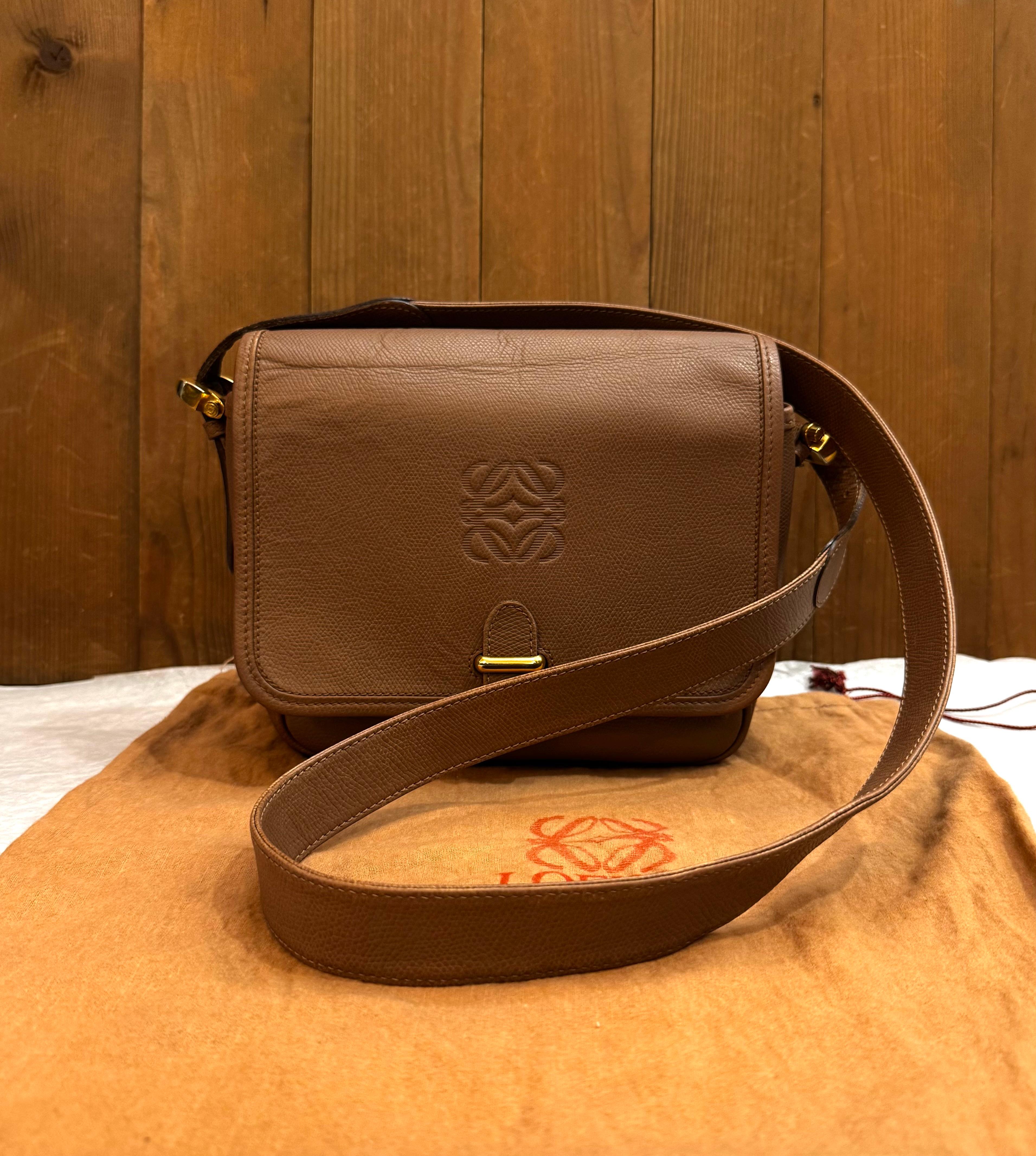 Diese LOEWE Anagram Crossbody Bag im Vintage-Stil ist aus strukturiertem Kalbsleder in Braun mit goldfarbenen Beschlägen gefertigt. Die Frontklappe öffnet sich zu einem bedruckten Innenraum mit zwei Fächern und einer Reißverschlusstasche.