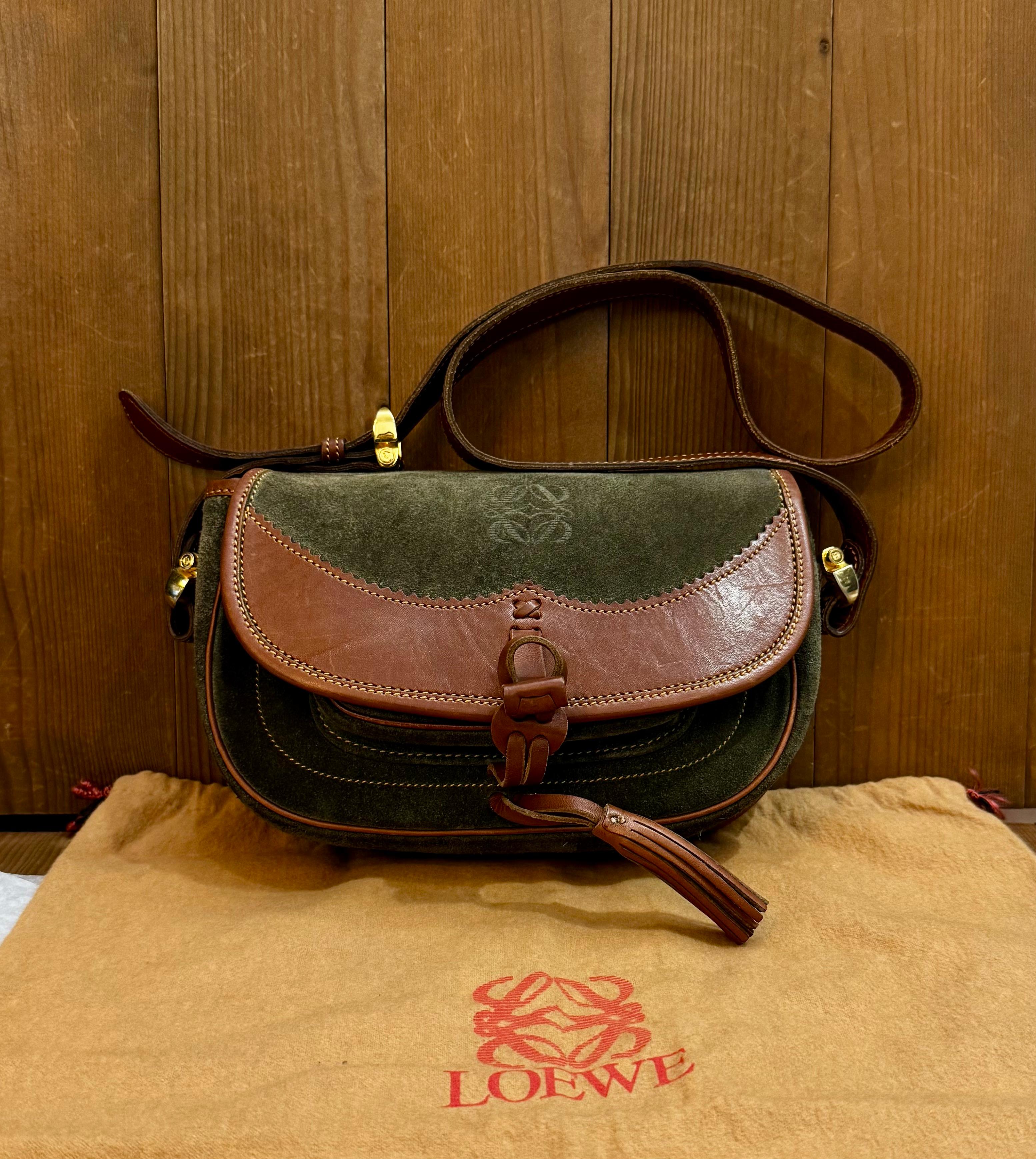 This vintage LOEWE Anagram crossbody bag is crafted of green suede and brown smooth calfskin leather featuring gold toned hardware. Front flap toggle closure opens to a smooth calfskin leather interior and a small front pocket with snap fastening.