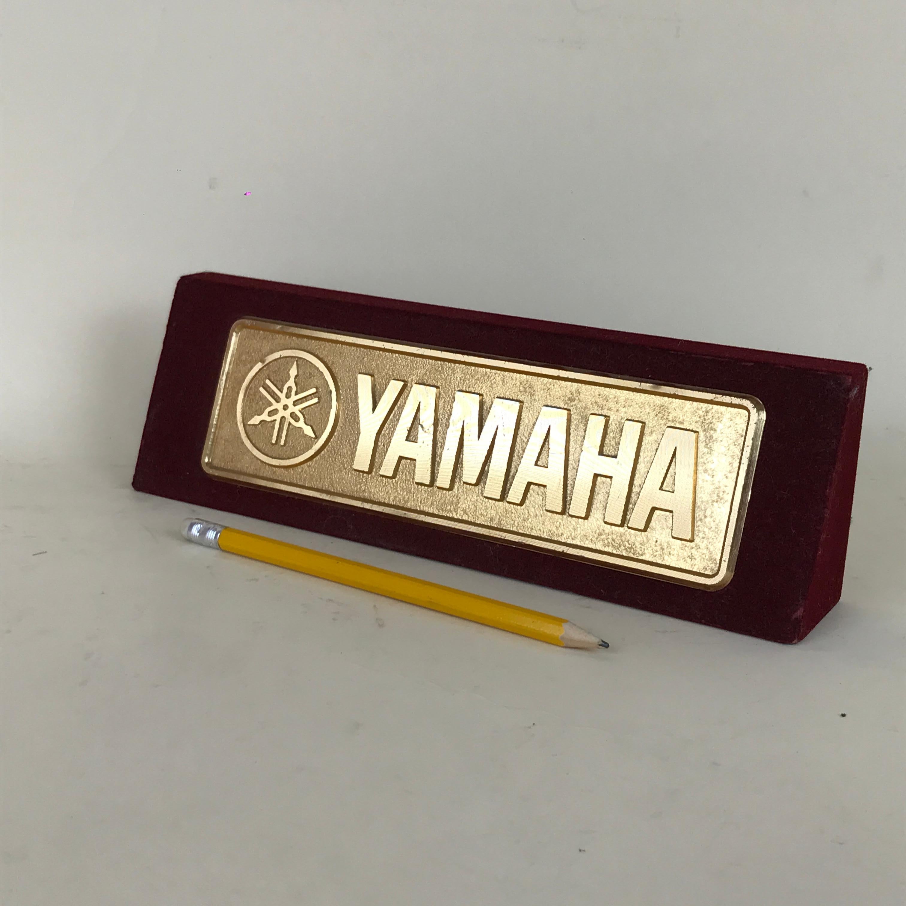 Vintage metal Yamaha logo display on bordeaux velvet.

Collector's note:

Yamaha Corporation is a Japanese multinational corporation and conglomerate with a very wide range of products and services, predominantly musical instruments, electronics
