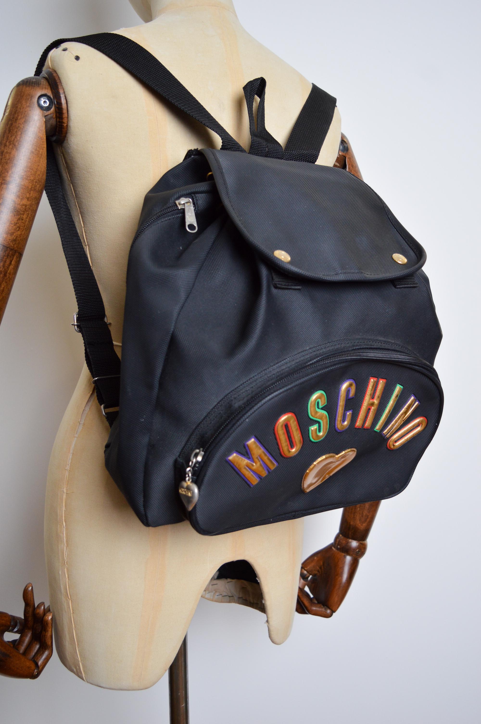Vintage 1990's Moschino black Vinyl Backpack bag, with large 'MOSCHINO' lettering.   An Iconic nineties Vintage Piece !   

MADE IN ITALY !   

Features: Large 'MOSCHINO' spell out letters, Top Handle, Single Zip fasten compartment, Adjustable draw
