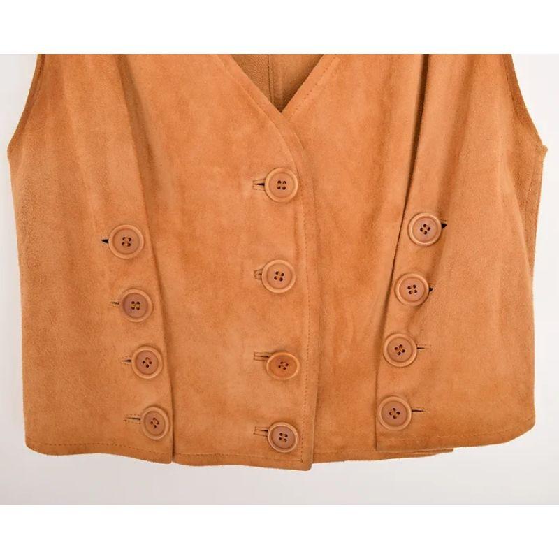 Vintage By 1990's Moschino tan waistcoat, fabriqué à partir d'un tissu doux et agréable à porter.  et daim souple.
Le gilet est doté d'un bouton ludique qui permet d'allonger et d'ajuster la coupe du vêtement. 

FABRIQUÉ EN ITALIE