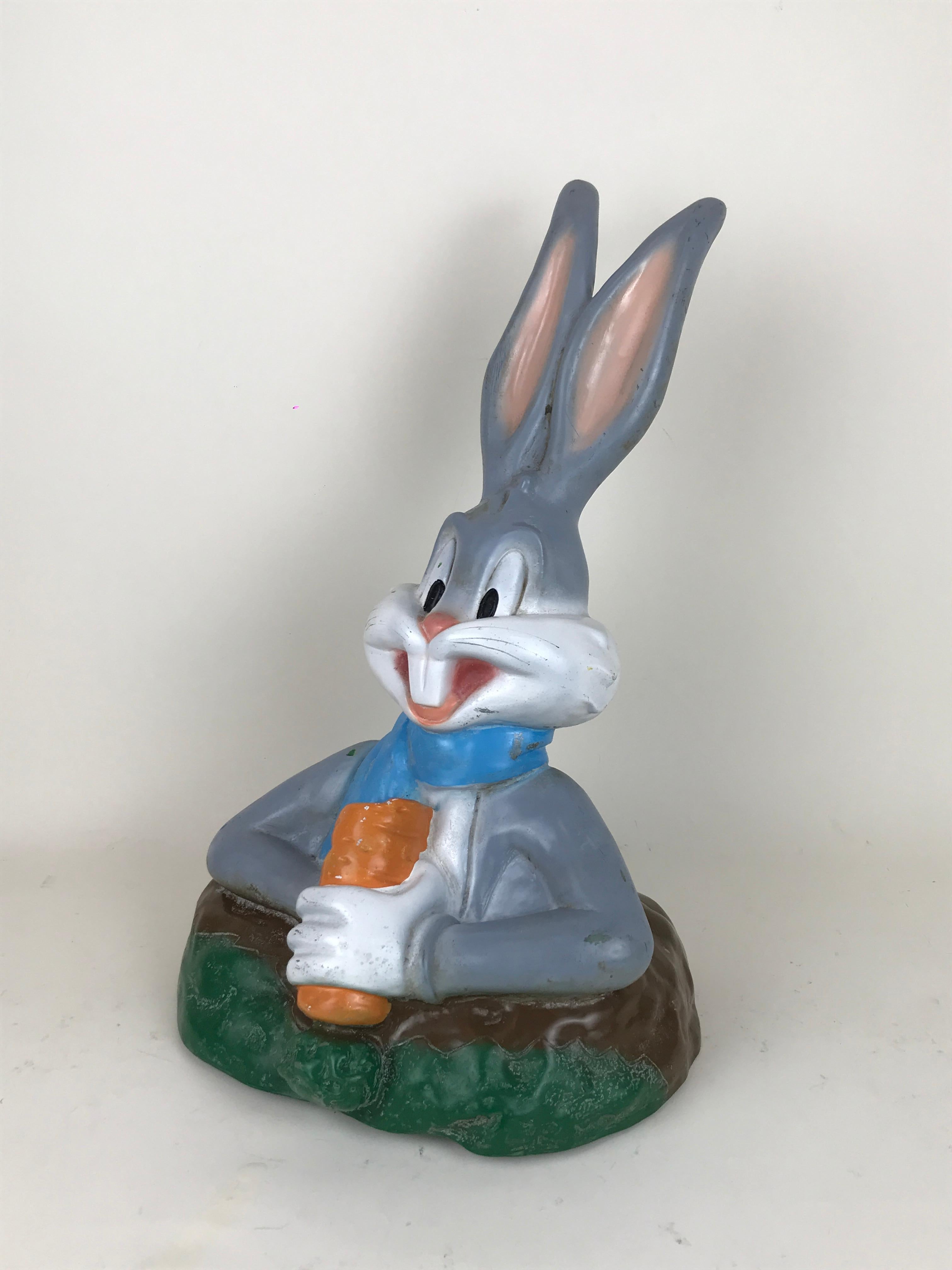 Vintage plastic half body sculpture of Bugs Bunny eating a carrot while standing from his rabbit hole. Made for Warner Bros. by Austrian maker Celloplast in the 1992.

Bugs Bunny holds a carrot and wears a blue scarf around the neck.

Marked TM