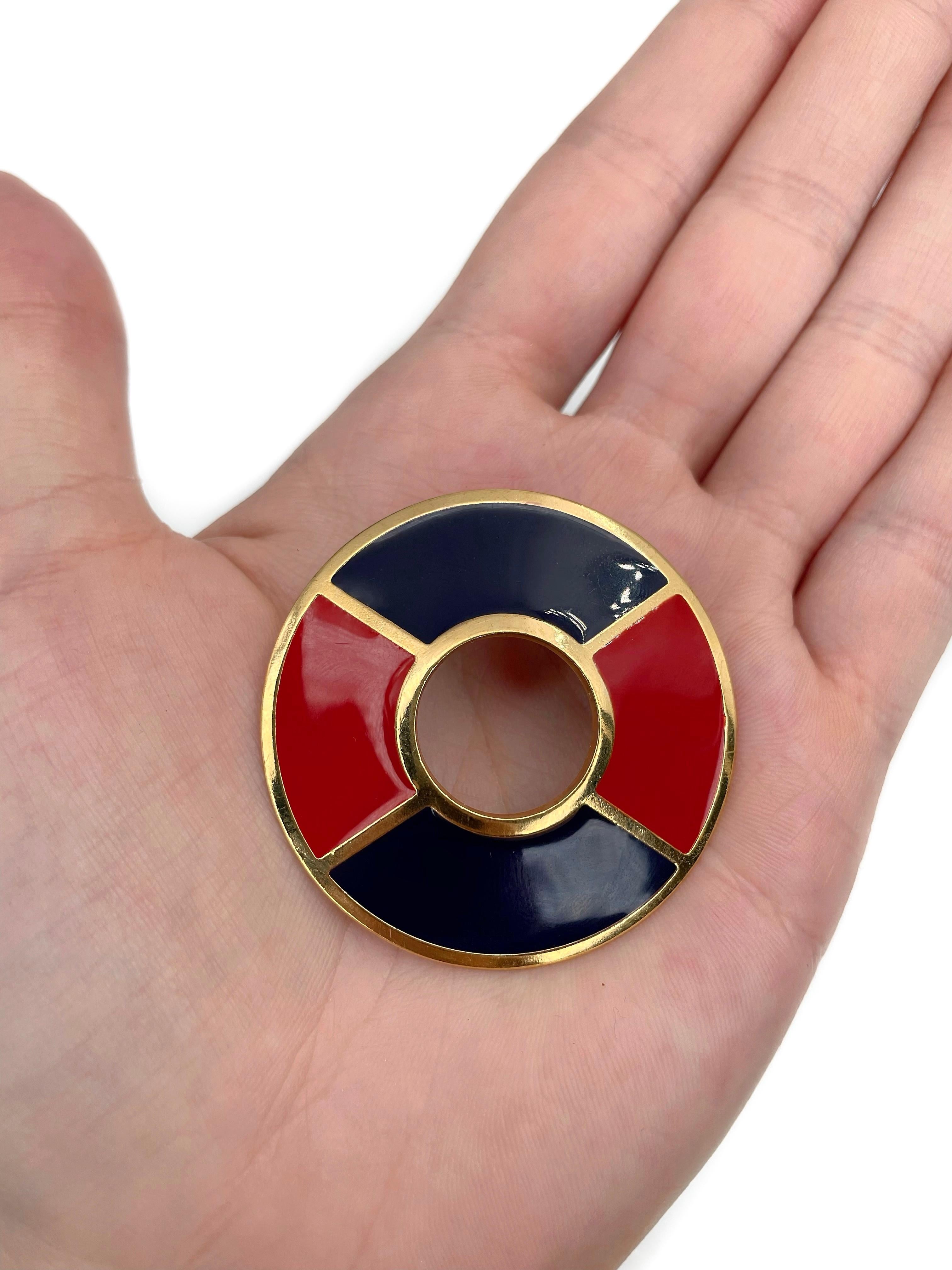 Il s'agit d'une broche ronde en or conçue par YSL dans les années 1990. La pièce est plaquée or. Il est orné d'émaux rouges et bleus. 

Signé : 