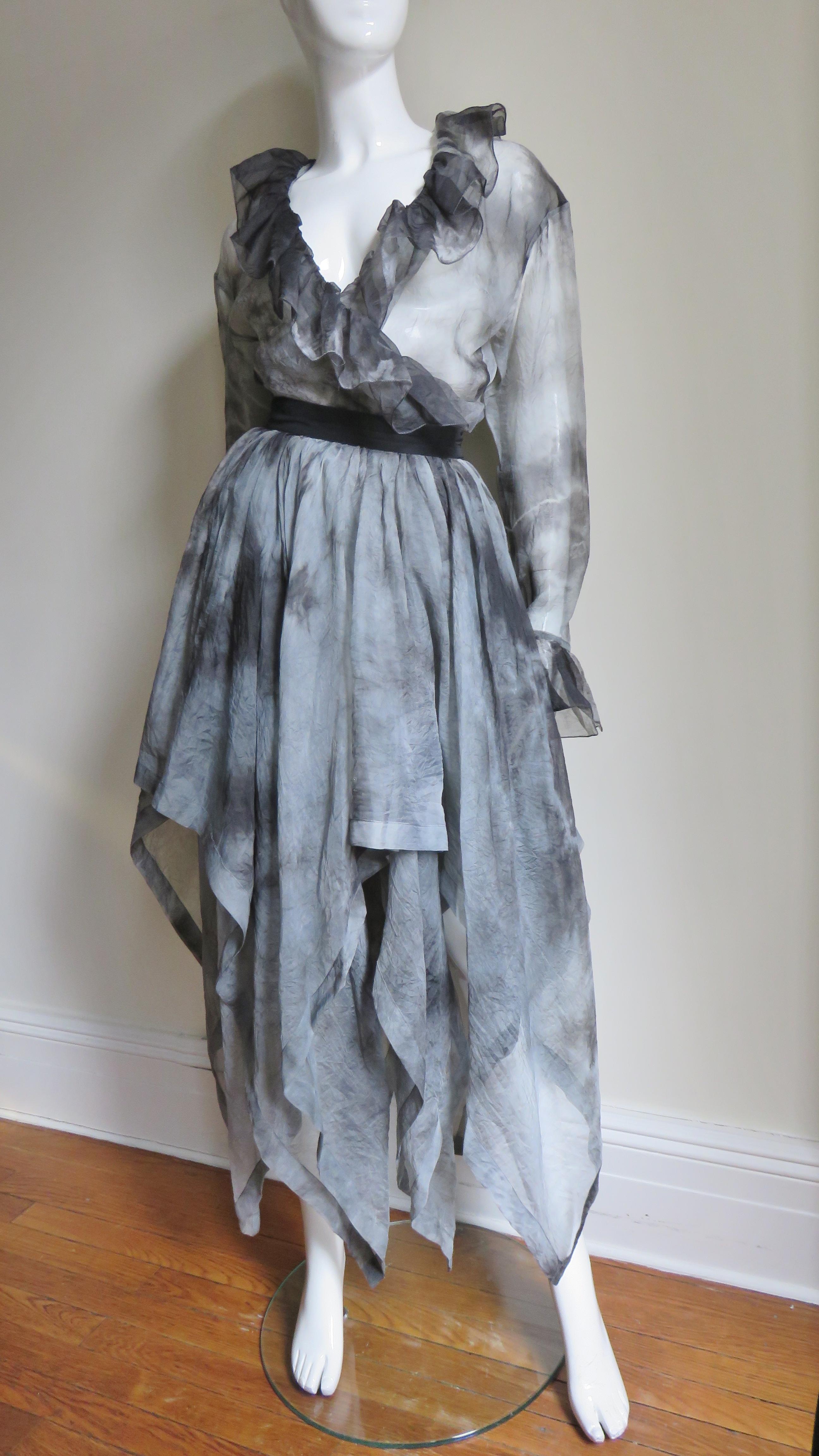 A fabulous semi sheer silk skirt and shirt set from Workers For Freedom, London in a grey and black tie dye pattern.  The long sleeve wrap or tie top has a ruffle around the neck, front and button cuffs. The skirt is comprised of 2 layers of