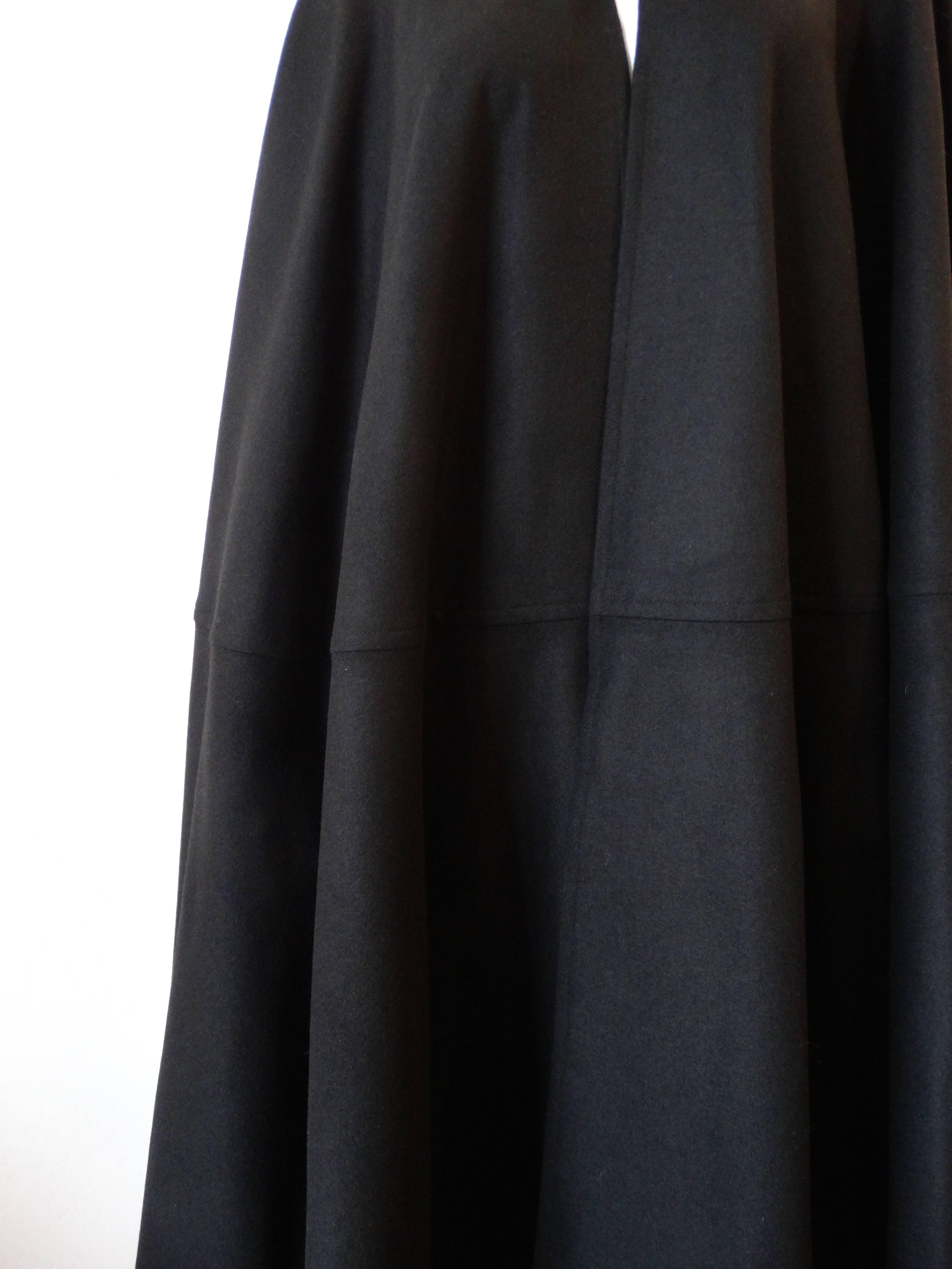 The 1990s does the 1970s with our amazing Yves Saint Laurent dramatic black cape! Made of a rich black wool fabric, this piece drapes beautifully on the body. Contrasted with multicolored rope closure at the neck, embellished with coral, lapis and