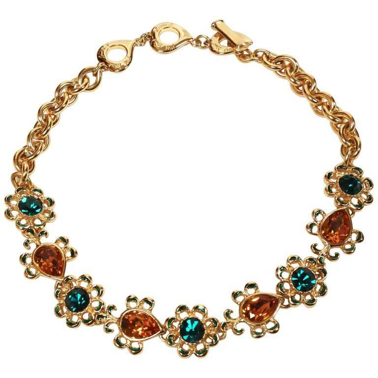 Shiny gilt metal necklace with topaz and emerald colored faceted glass stones and green enamel accents designed by Yves Saint Laurent dating to the 1990's. Removable drop piece hooks on to the necklace. Toggle closure. Made in France. Excellent