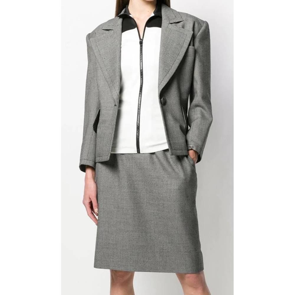 Yves Saint Laurent gray wool suit. The jacket with classic lapel collar, front button closure, long sleeves, two flap pockets; knee-length skirt, high waist with side zip and button closure, welt pocket.

Years: 80s

Made in Italy

Size: 44