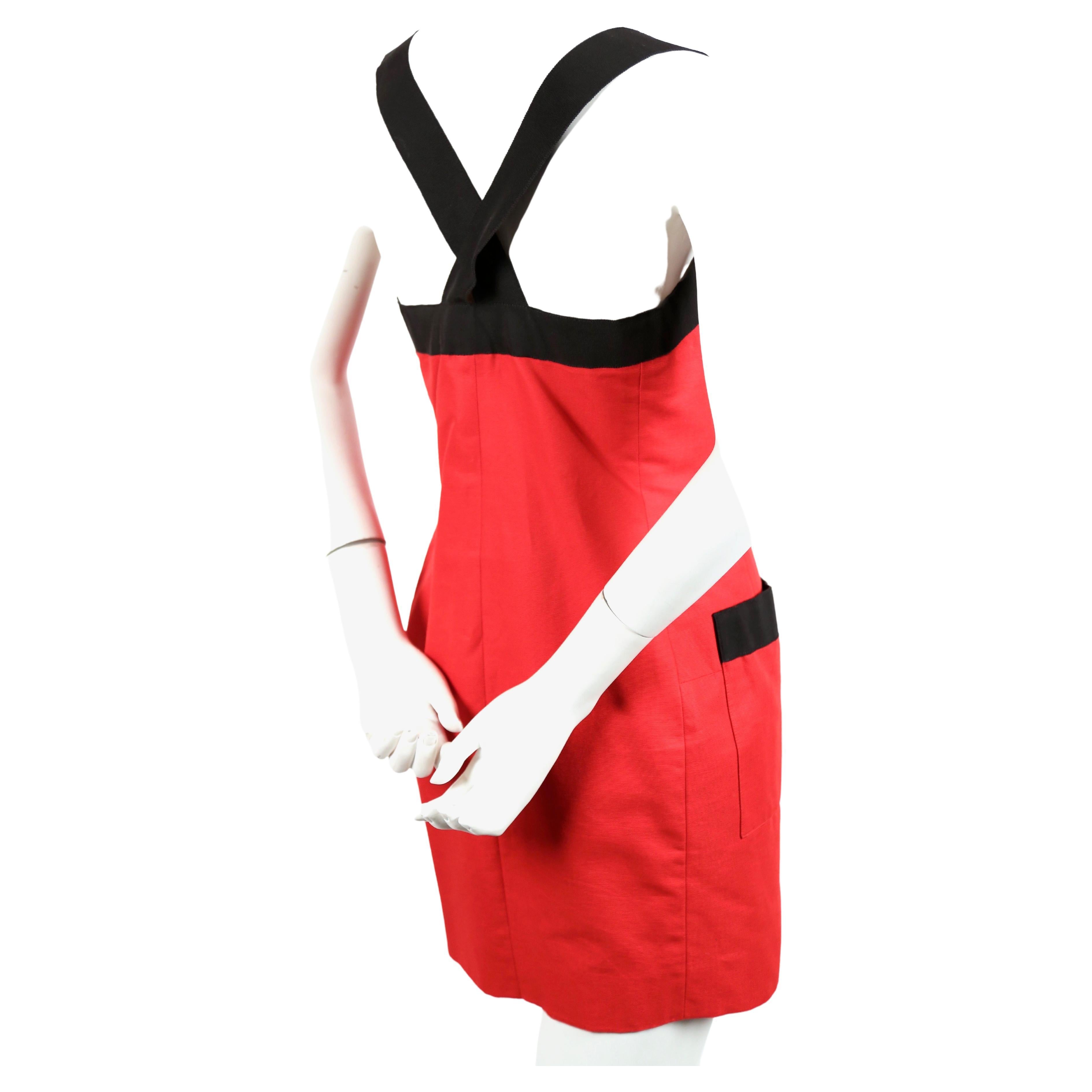 Red cotton mini dress with wide black grosgrain ribbon trim by Yves Saint dating to the 1990's. Dress is labeled a French size 40. Dress measures approximately: 36” at bust, 32” at waist and at the hips 36”. Button front closure. Fabric content: