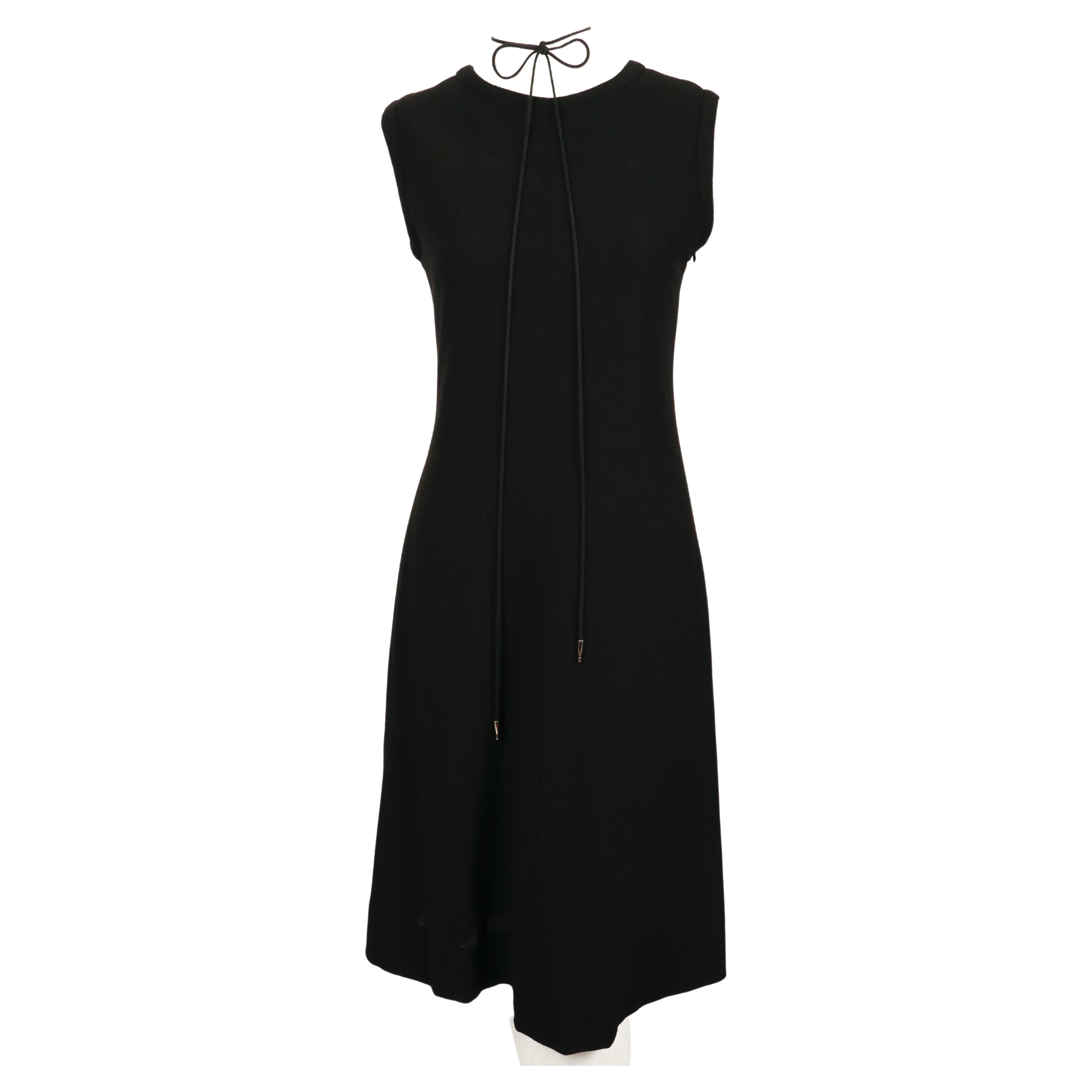 Robe en laine noire de jais avec dos à lacets conçue par Yves Saint Laurent au début des années 1990. La robe a une légère forme en A. Les cravates ont des extrémités en métal argenté brillant et peuvent être portées de différentes manières. De