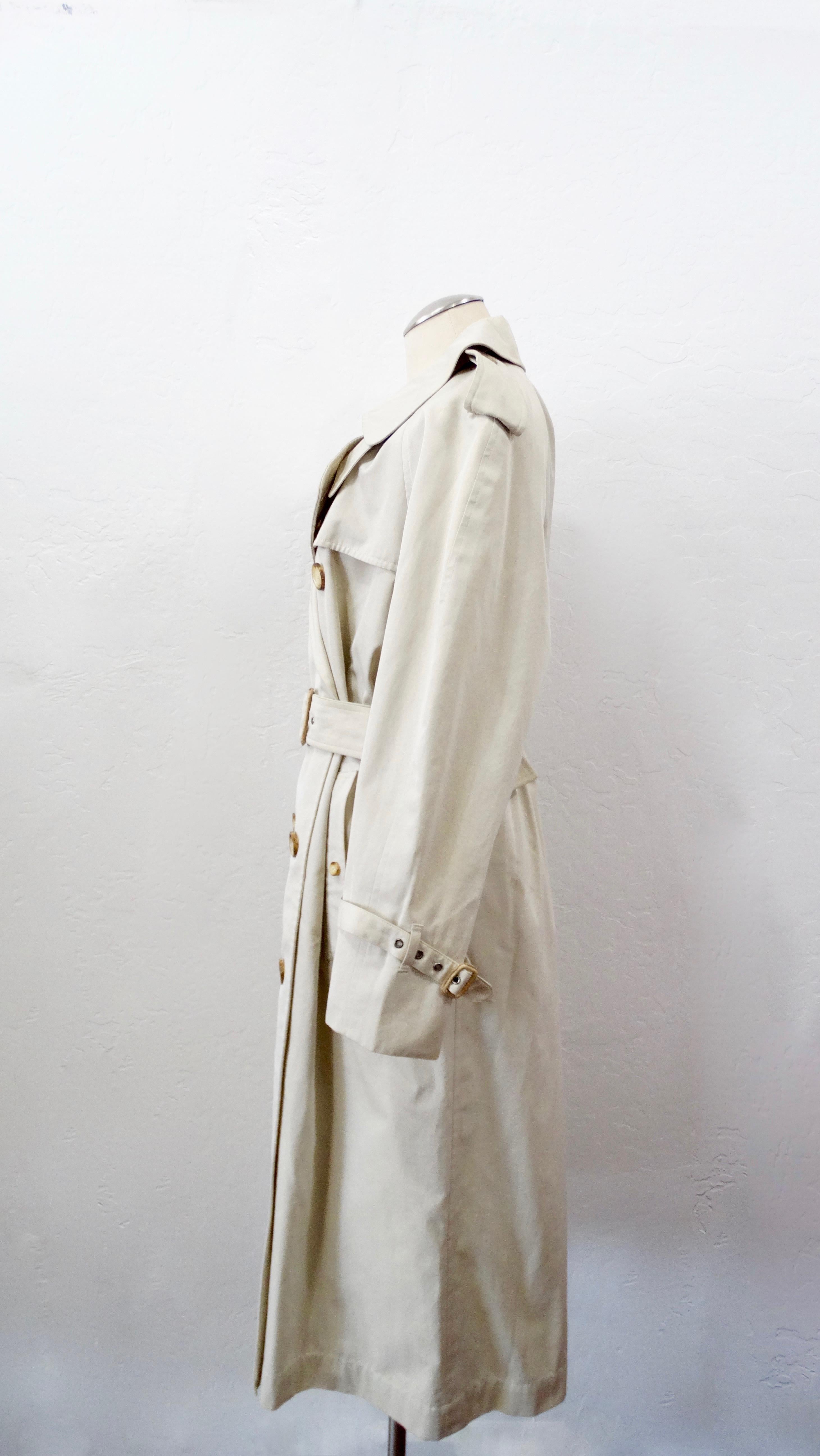 Your perfect trench coat is here! Circa 1990s, this timeless Yves Saint Laurent trench coat is made of 100% Cotton and is a gorgeous soft tan color. Features epaulettes on the shoulders, notched lapels, double breasted front tortious shell buttons,