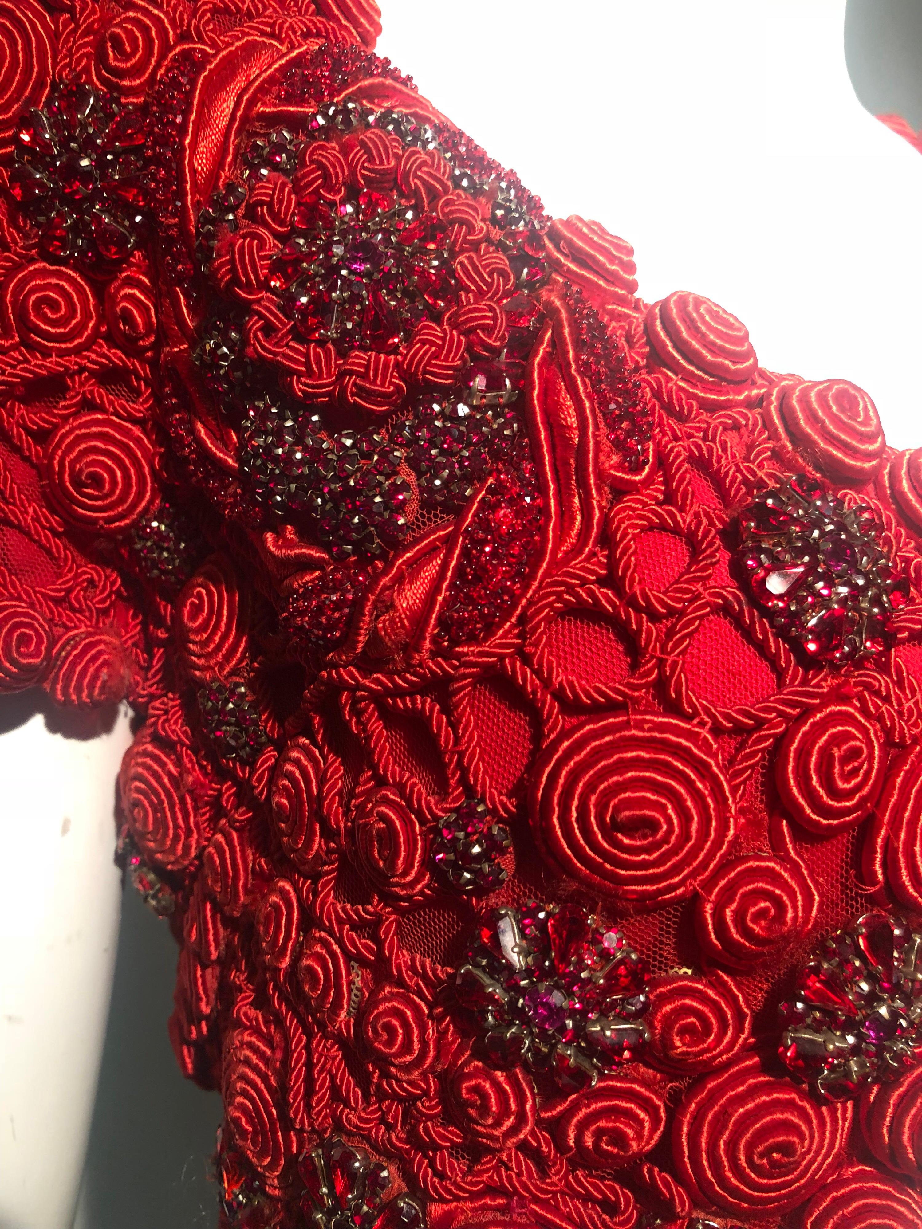 This 1991 Atelier Versace by Gianni Versace, ruby red prong-set crystal & cord embroidery embellished cropped jacket is a striking piece that would compliment jeans or a ball gown with equal aplomb! A single hook and eye closure at neckline.