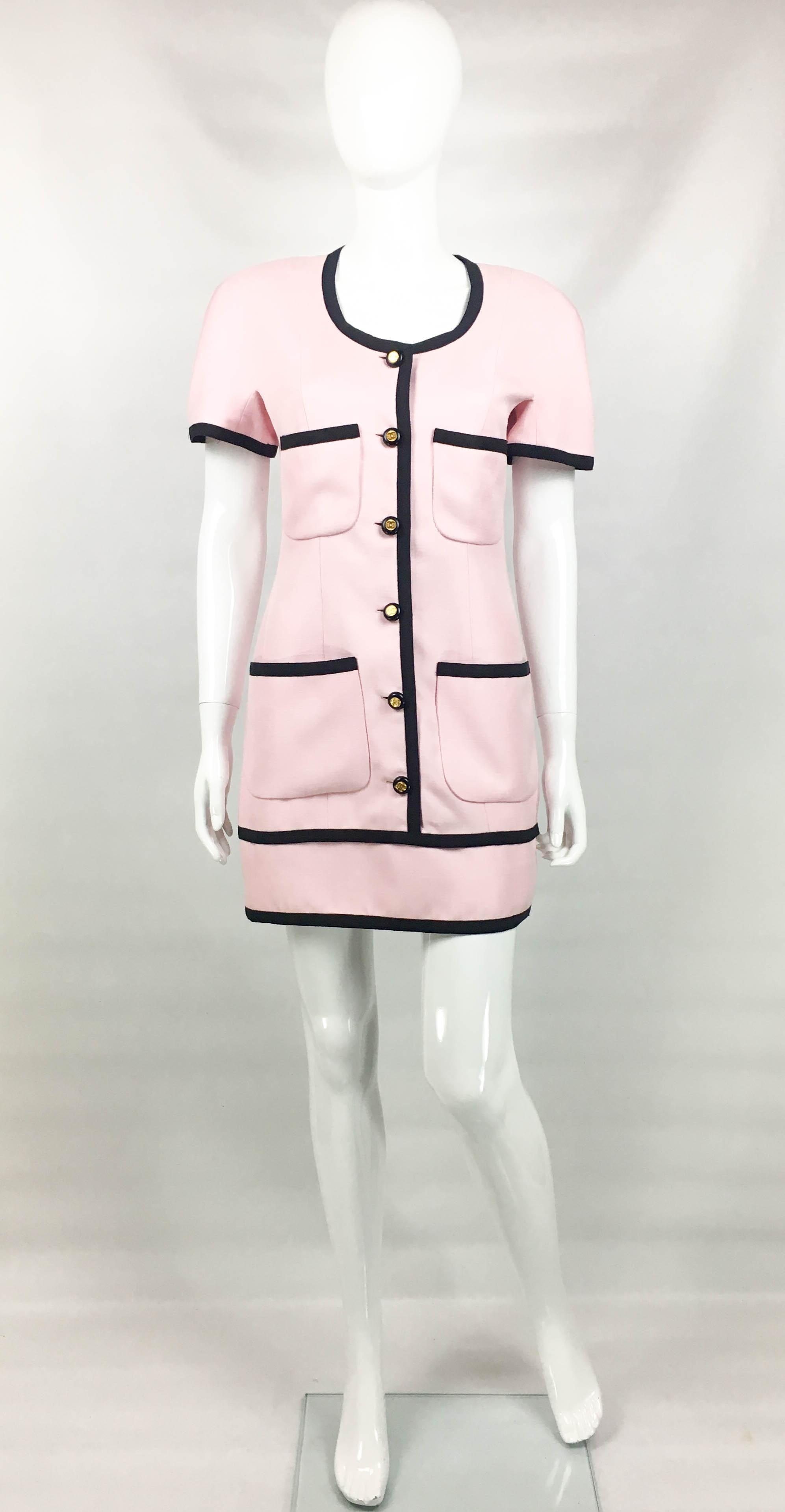 Vintage Chanel Pink Dress with Logo Buttons. This gorgeous short dress by Chanel dates back from 1991. Made in pink viscose, it has short sleeves, black edgings and black resin buttons with a gilt centre featuring the iconic ‘CC’ logo. There are 4