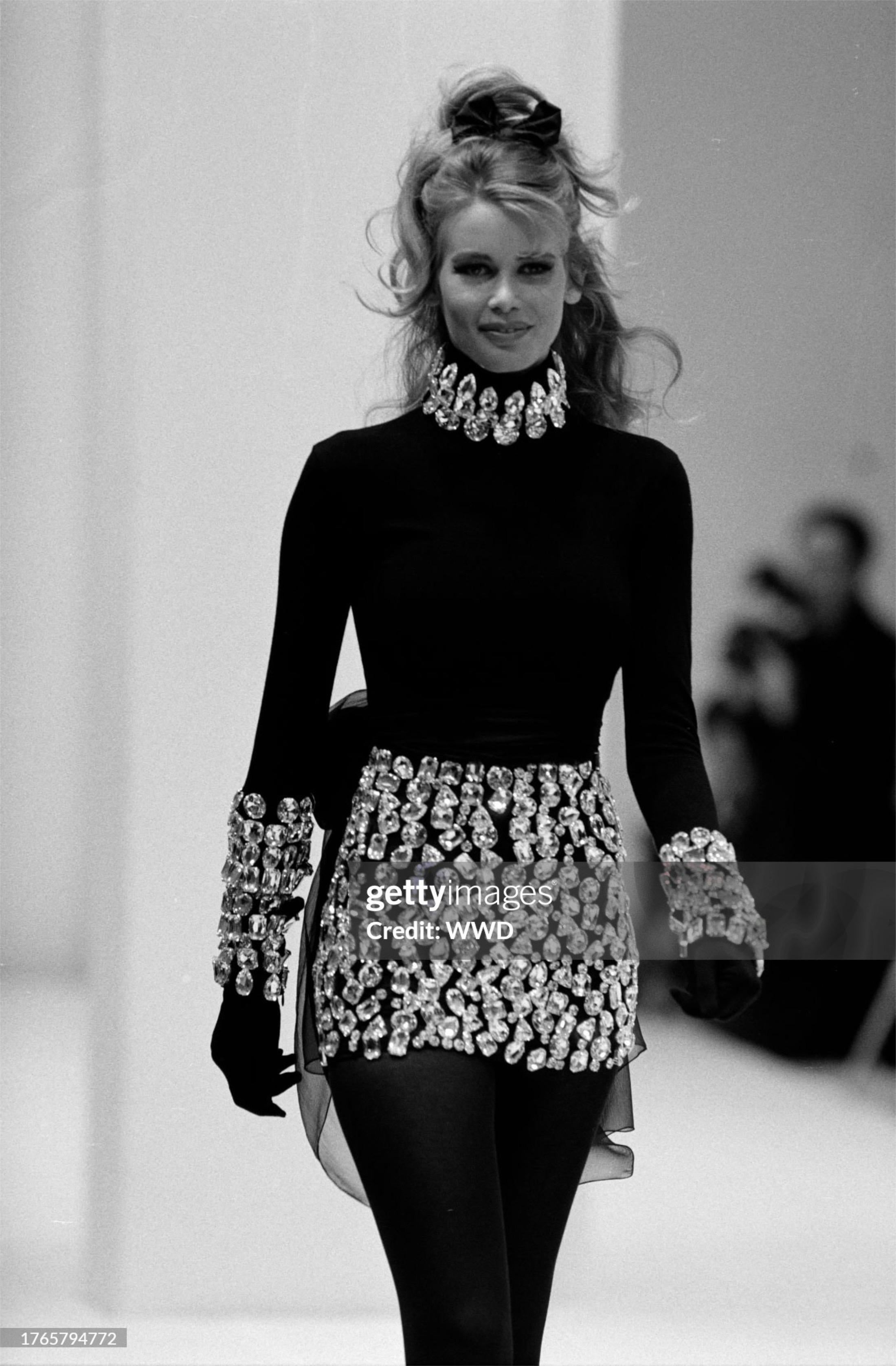 Très séduisant et très convoité, cet ensemble composé d'un haut et d'une jupe en maille de laine extensible noire, rehaussé de strass, date de la collection automne-hiver 1991 de Dolce & Gabbana. Un look iconique qui incarne parfaitement la fusion